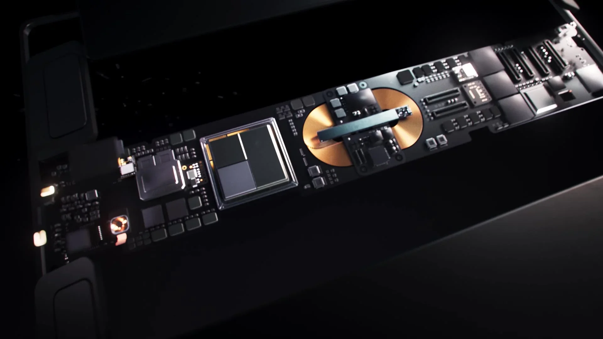 Close-up of a high-tech computer motherboard with various electronic components, including a large gold-colored circle and a metallic arm, set against a dark background.