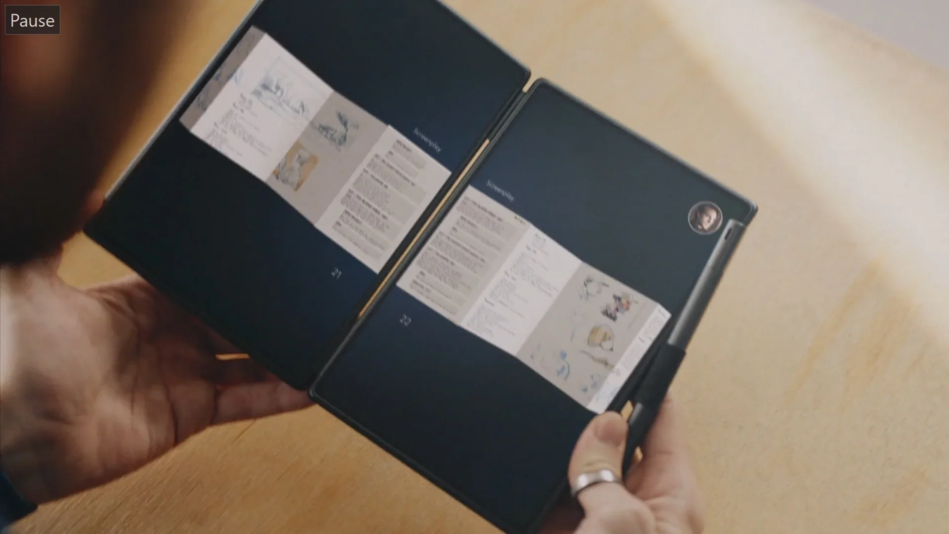 A person holding a foldable smartphone displaying unclear content on its screens.