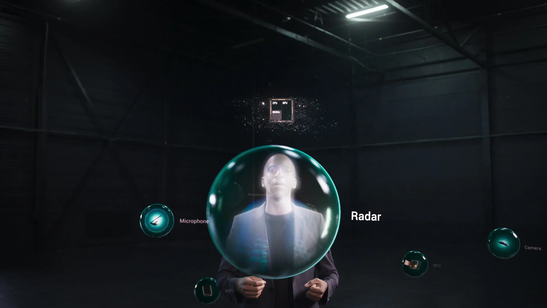 A person in a dark room surrounded by floating labeled digital icons and bubbles, including a large bubble with a human face inside, including labels for 'Microphone,' 'Radar,' 'NFC,' and 'Camera.'
