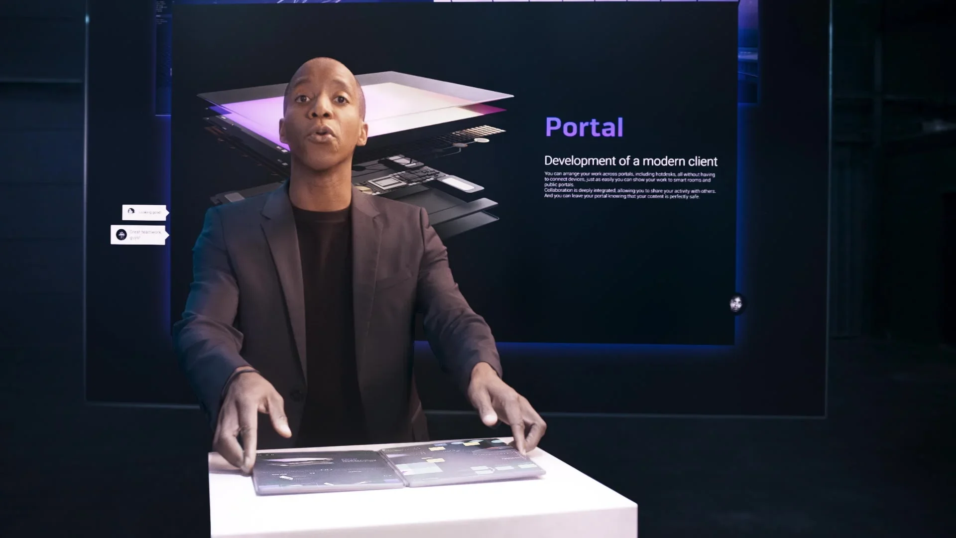 A man in a black blazer and black shirt standing at a white table, gesturing towards transparent digital panels with a large screen behind him displaying information about a 'Portal' development project.