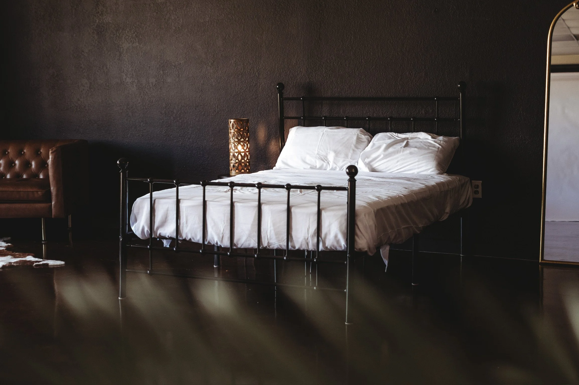 Cozy bedroom setup with a black metal bed frame and white bedding inside our natural light content creation studio on the Mississippi Gulf Coast.