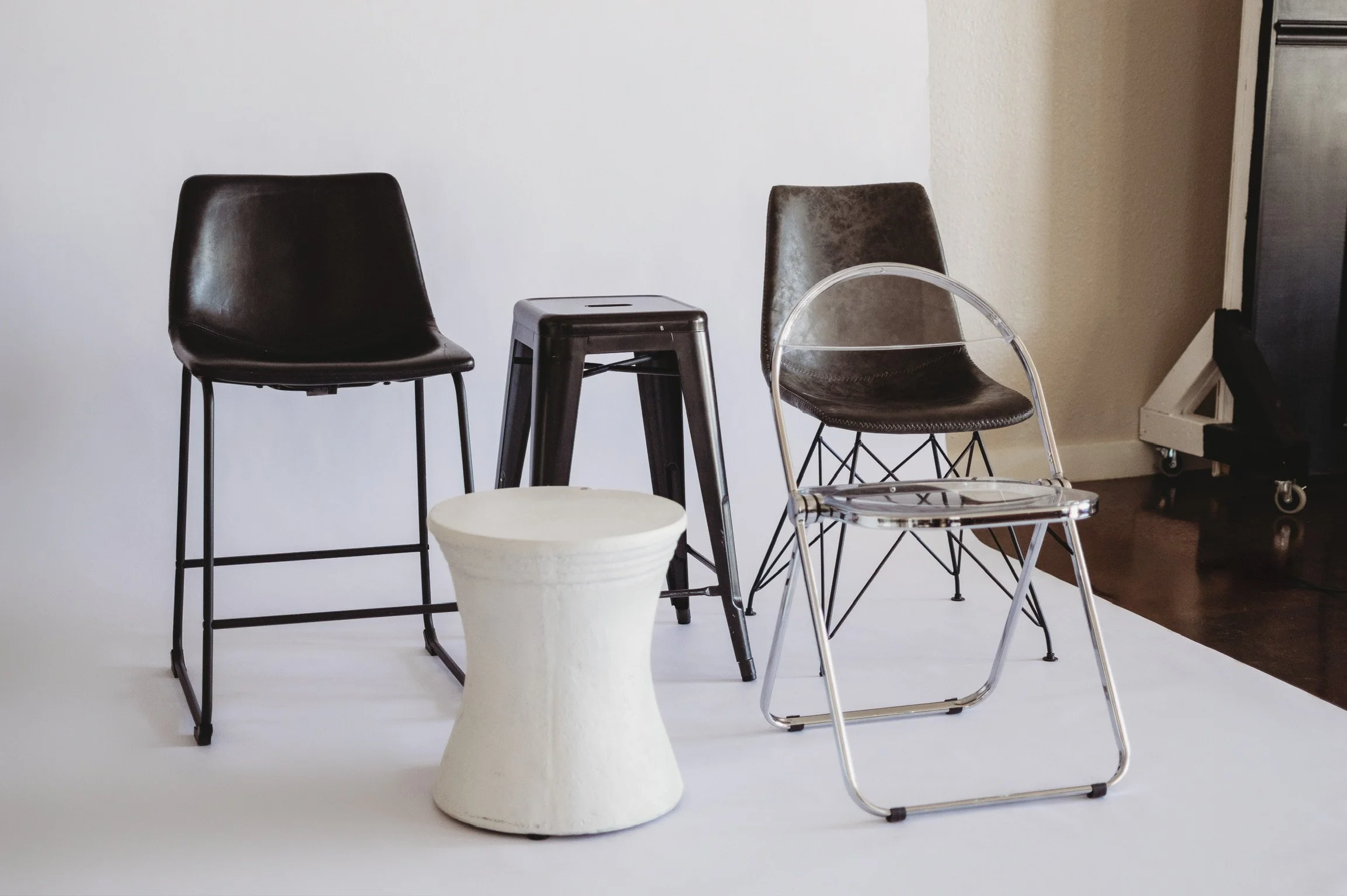 Collection of modern seating options including a clear acrylic chair and black leather chair for branding photoshoots at our Biloxi MS area studio.