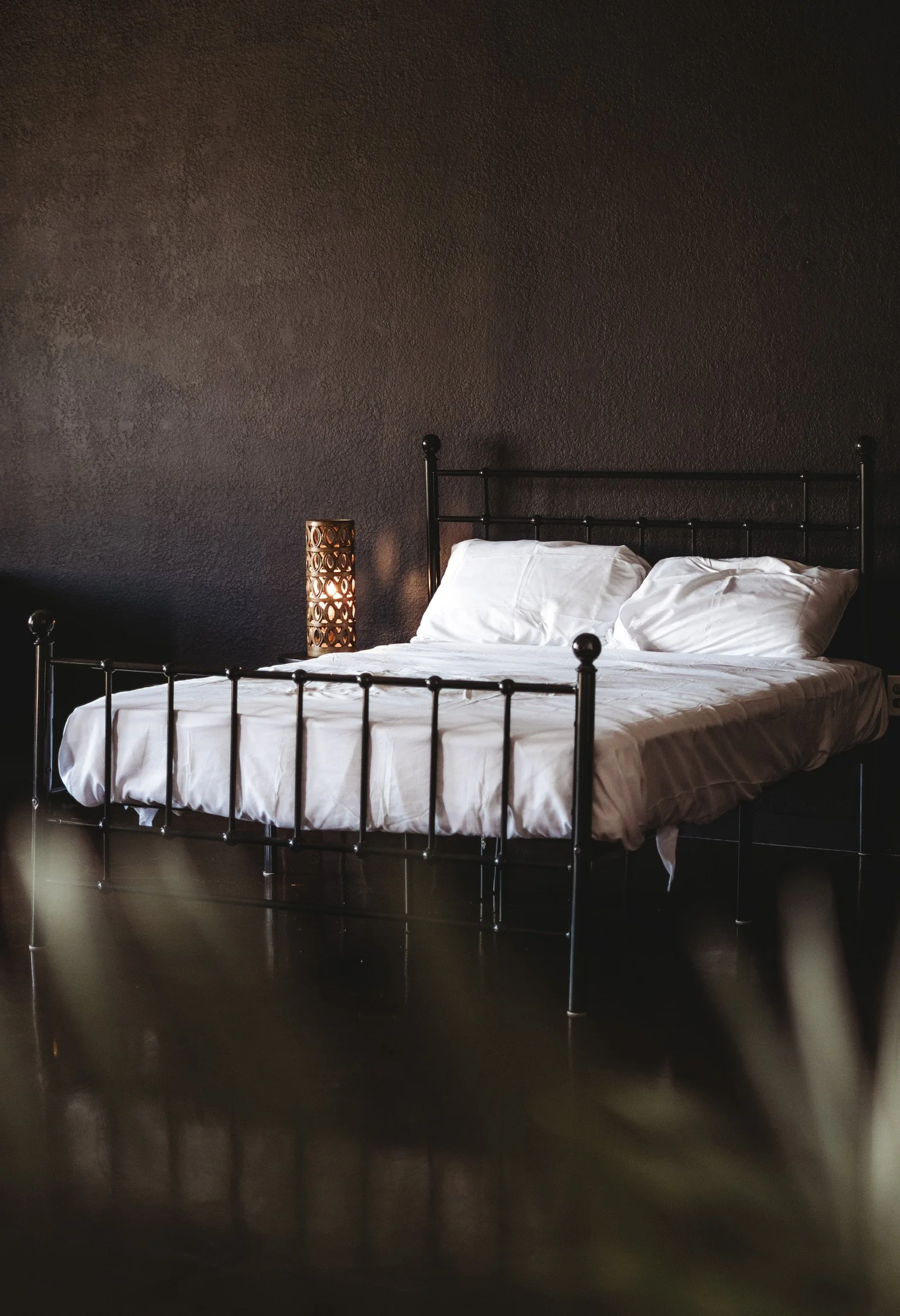 Cozy bedroom setup with a black metal bed frame and white bedding inside our natural light content creation studio on the Mississippi Gulf Coast.