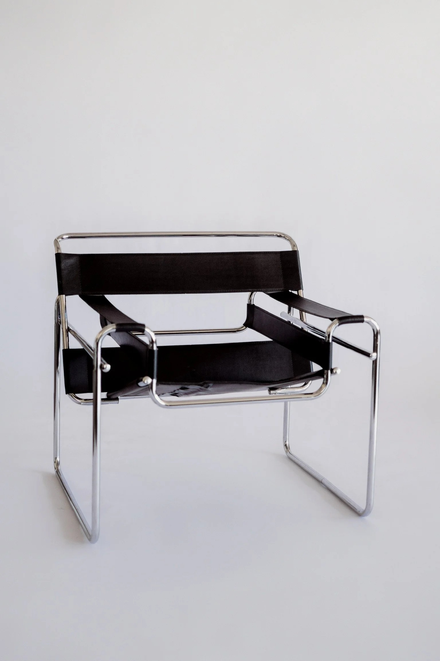 Modern minimalist chrome and black chair against a seamless white backdrop at our Mississippi Gulf Coast photography studio rental.