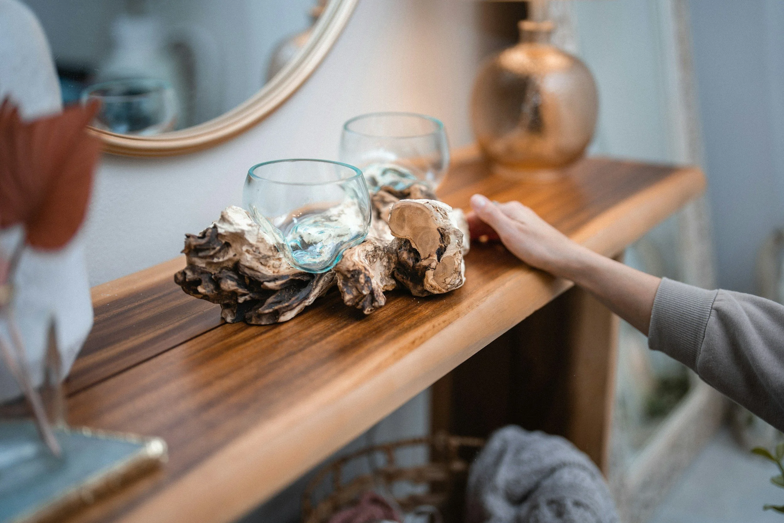 Wooden console table with decorative glass bowls and driftwood centerpiece