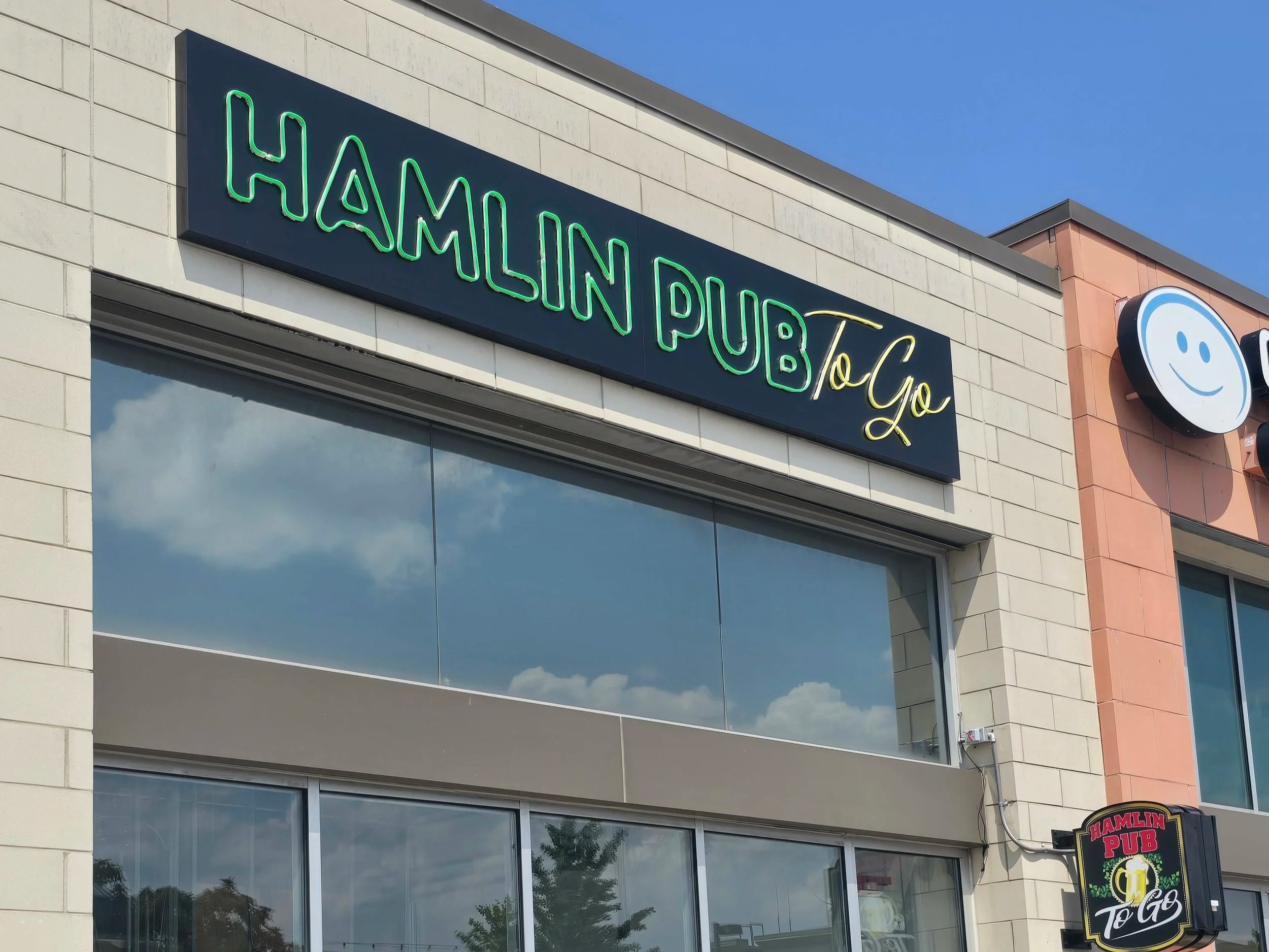 Custom sign for Hamlin Pub To Go with neon lettering on the building's exterior.