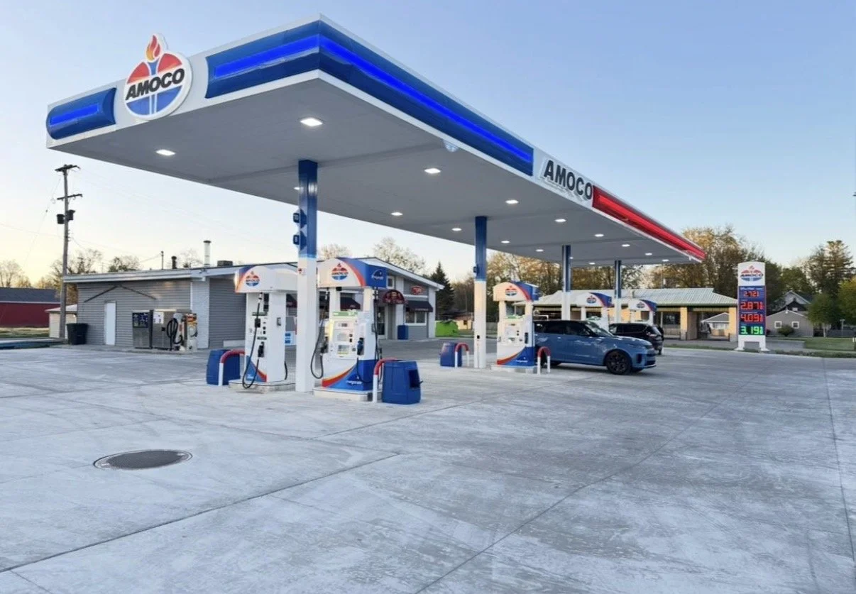 Amoco gas station canopy with fuel pumps and digital price sign, example of commercial fuel station signage.