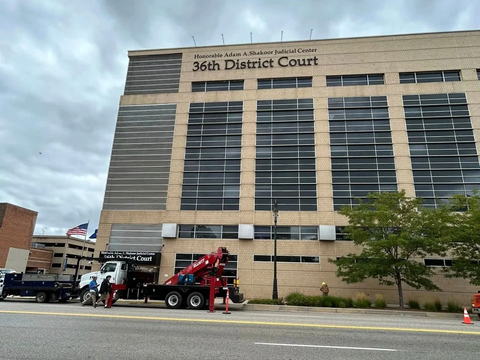 A large courthouse building labeled '36th District Court' with custom signage. Sign installers and truck parked along the street in front of it.