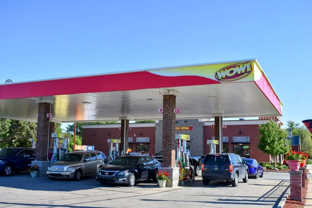 WOW gas station canopy and branding with multiple fuel pumps and convenience store, example of custom fuel station signage.