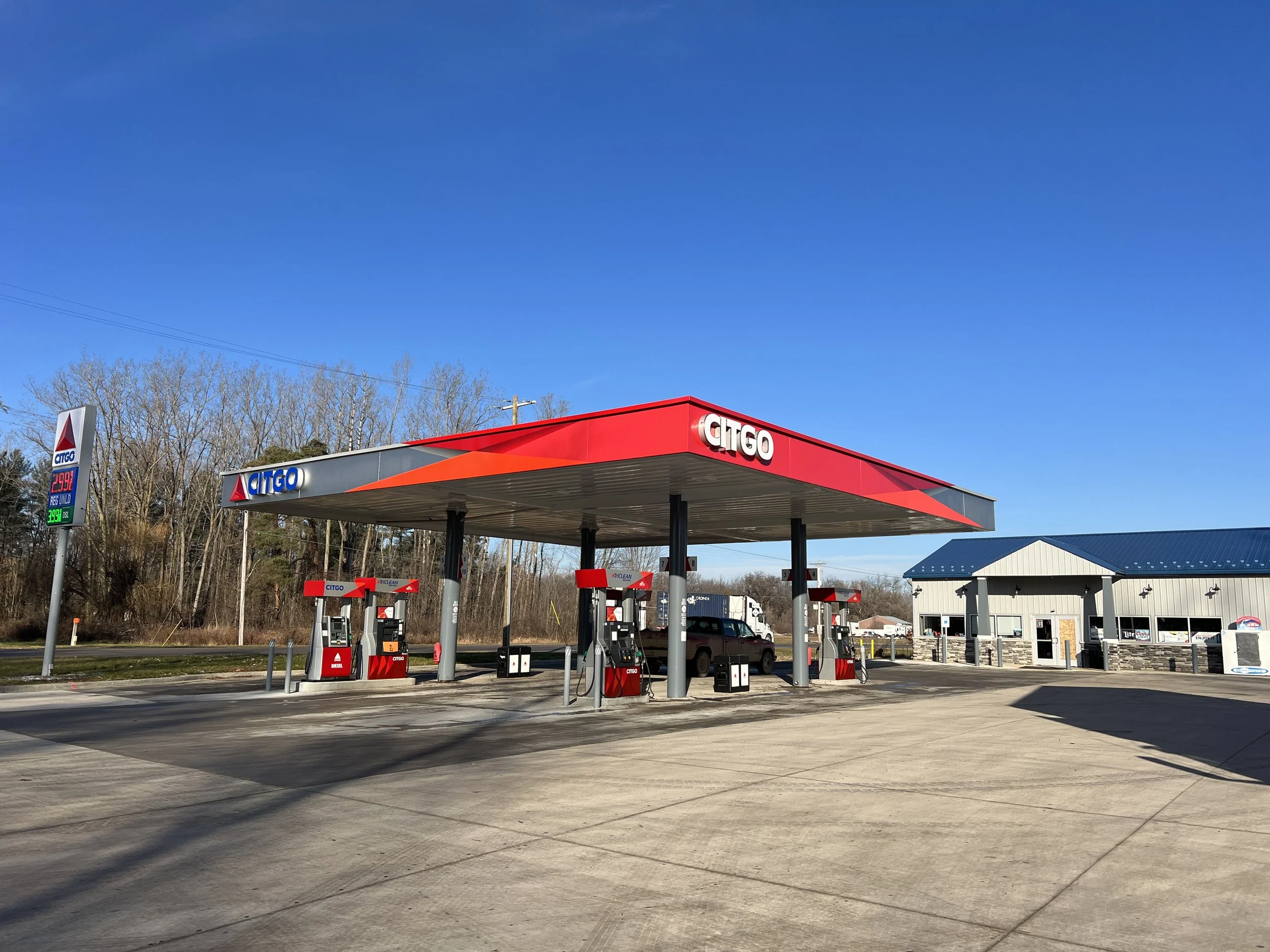 Illuminated CITGO gas station canopy and fuel price sign with four pumps, example of petroleum fuel station signage.