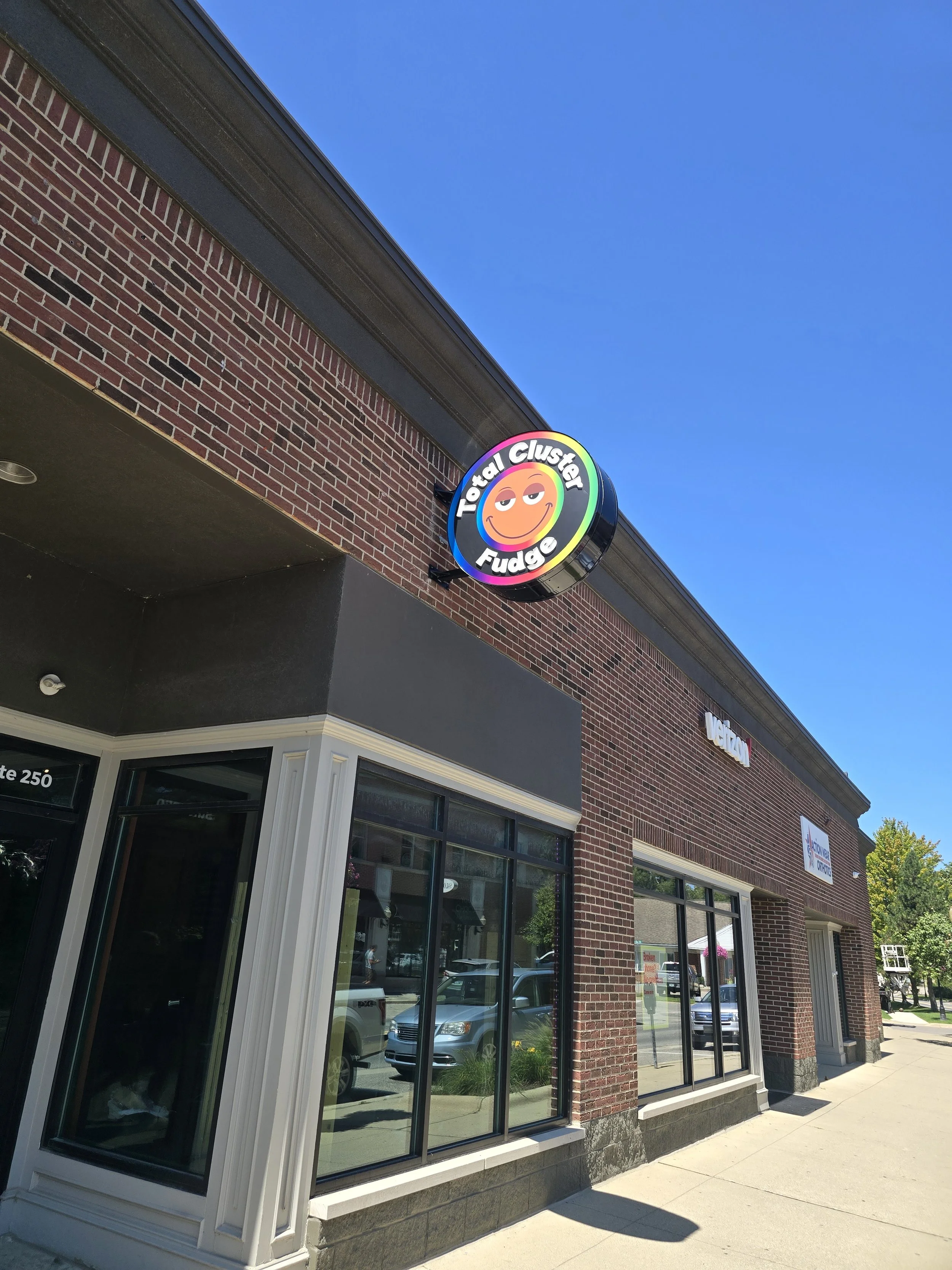Exterior view of a brick storefront with a round custom neon sign.