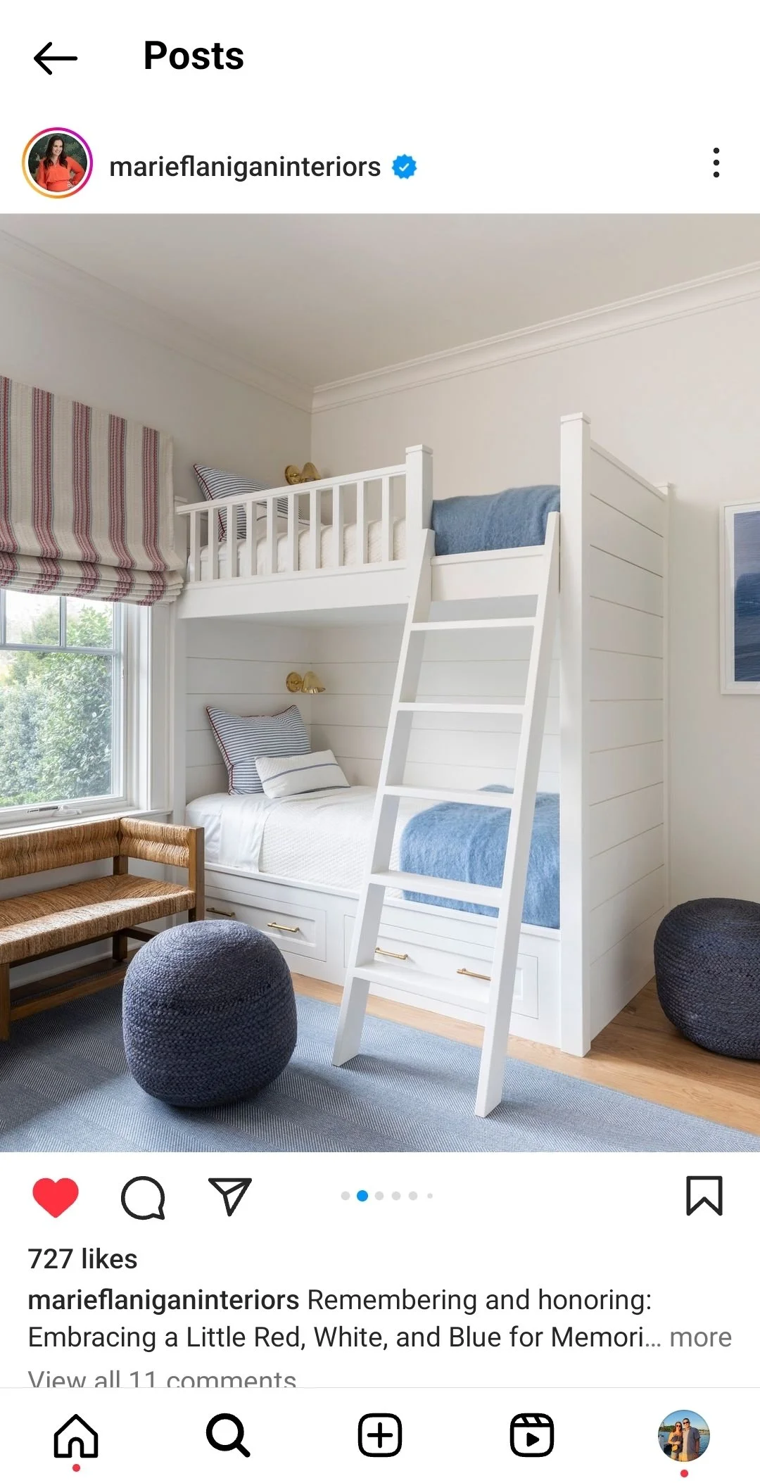 Bedroom with a white bunk bed, blue and white bedding, striped pillows, wooden bench, and round black poufs, featuring a large window with a red, white, and beige striped window shade.