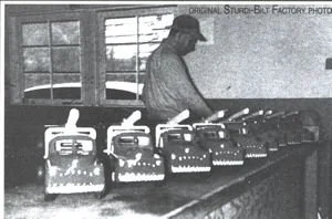 A person working at a table with several model train engines on display.