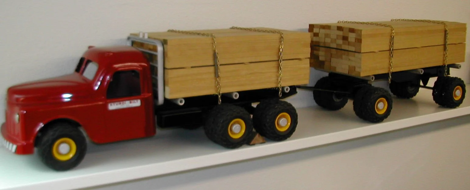 Toy red truck with wooden planks loaded on its trailer, used as decoration.