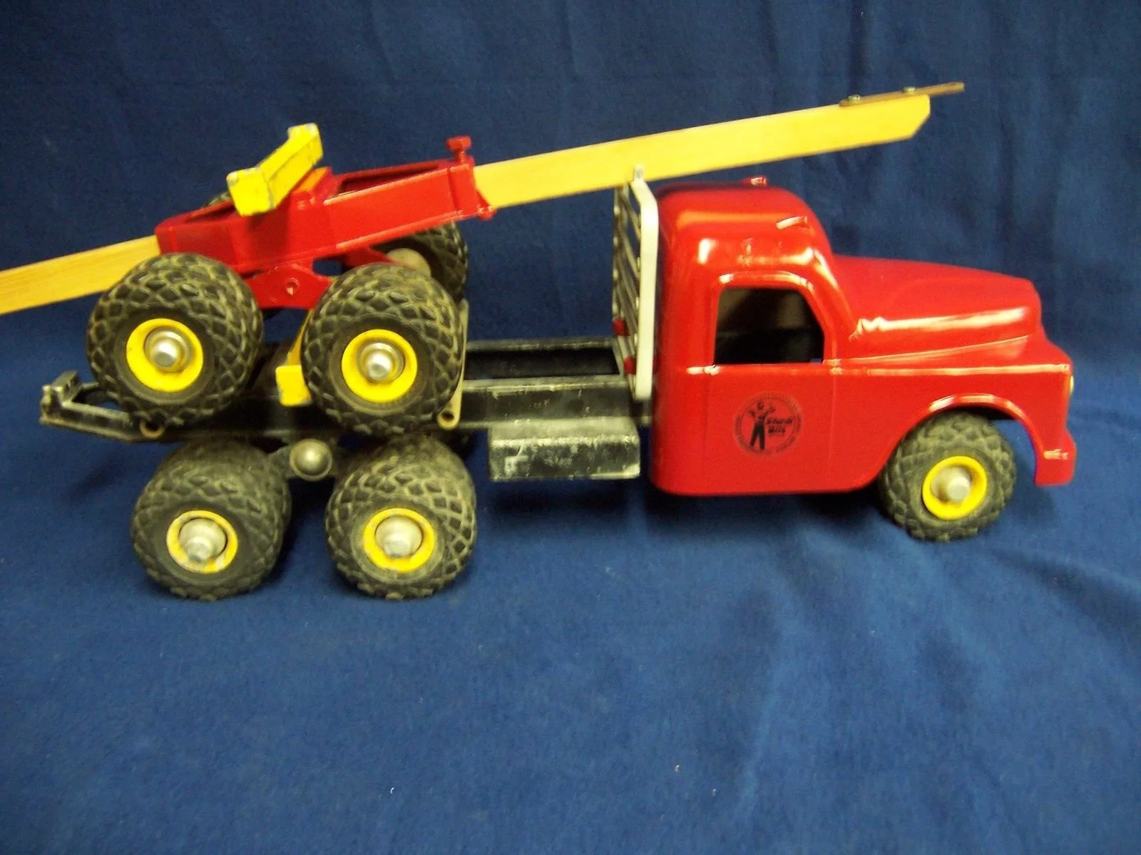 Toy red truck with black and yellow wheels carrying a red and yellow toy ladder