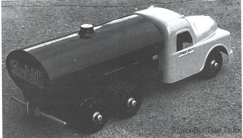 A toy model of a Stuart Blt Tank Truck with a black tank, white cab, and small wheels, placed on a textured surface.