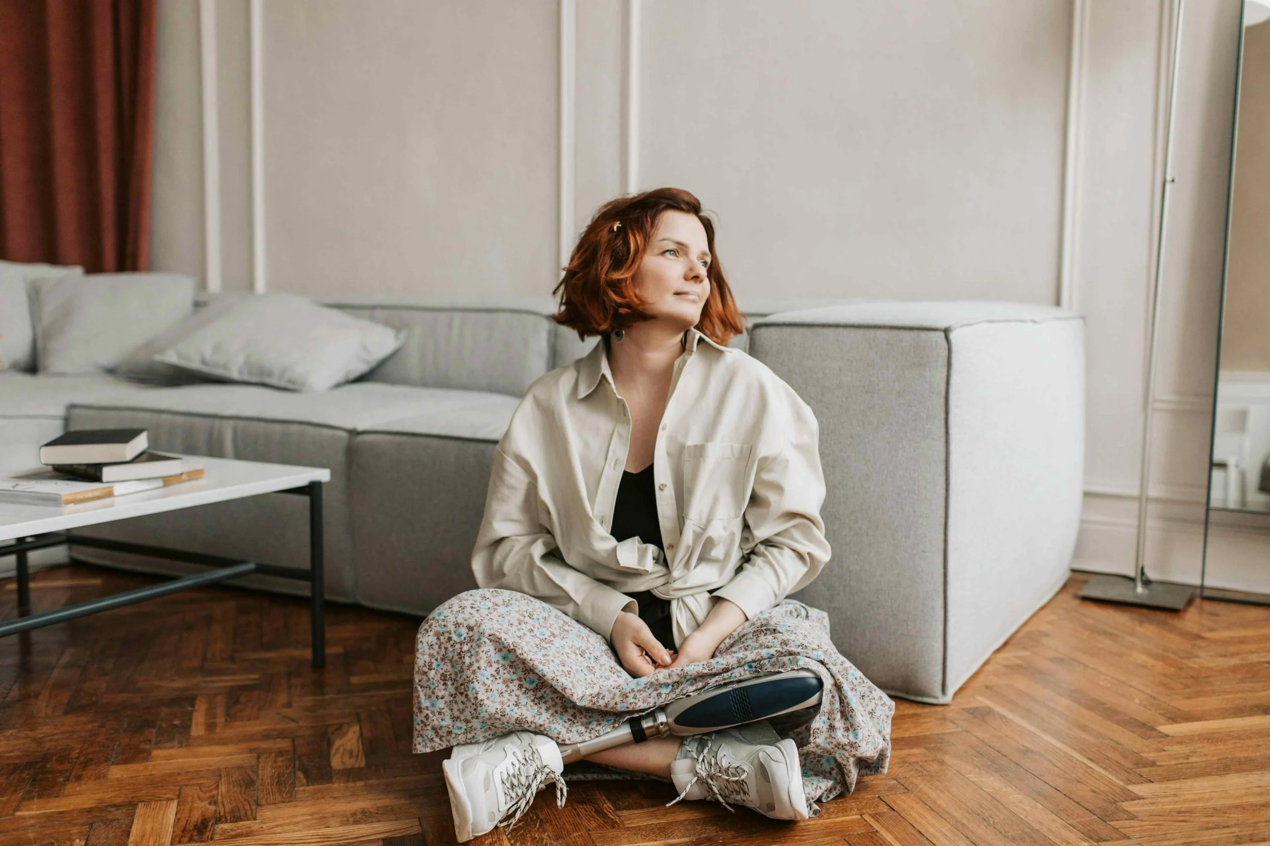 women with amputated leg sitting cross legged on the floor smiling
