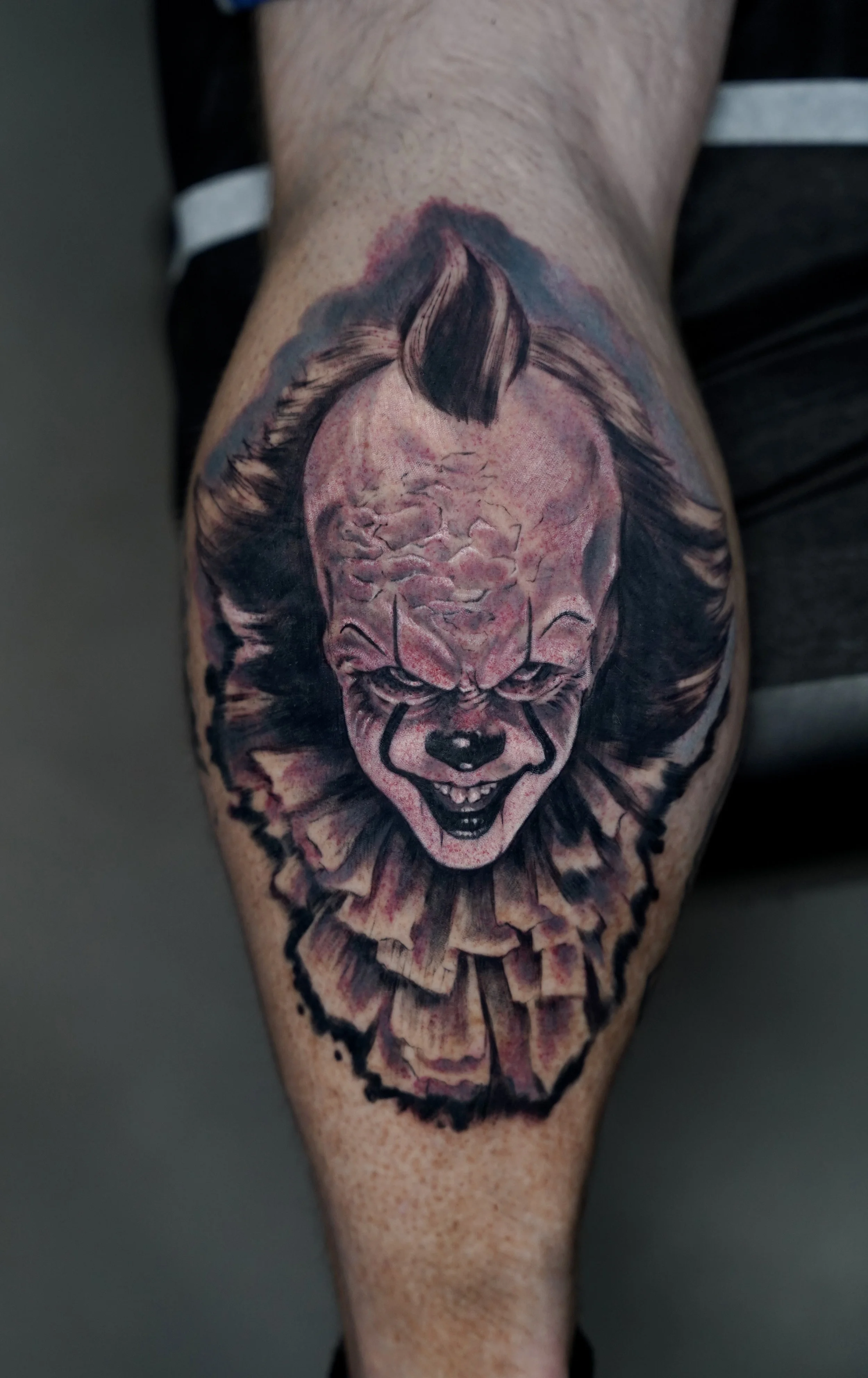 Tattoo of Pennywise the clown from Stephen King's IT on a person's forearm.