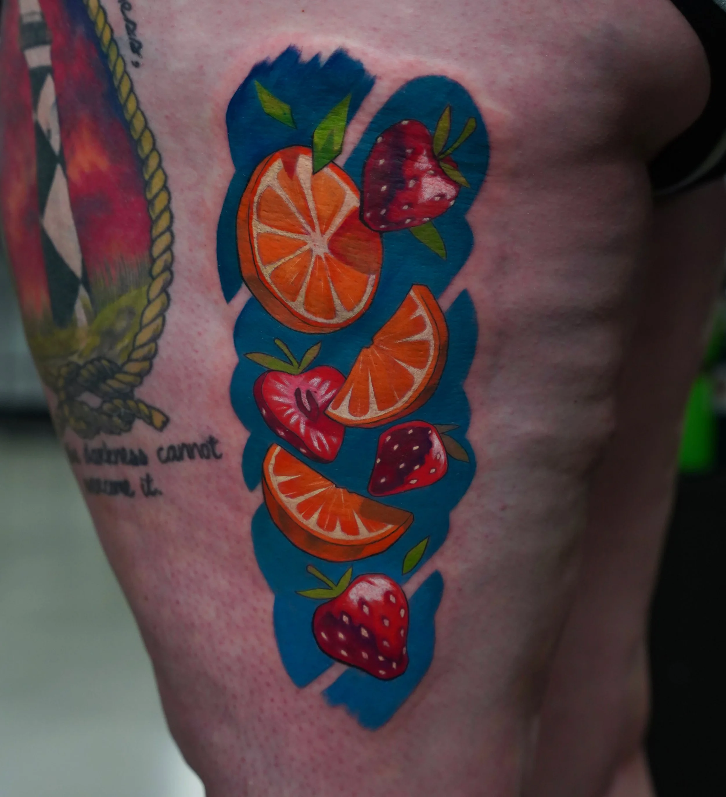 Colorful tattoo of strawberries, orange slices, and orange wedges with green leaves on skin.