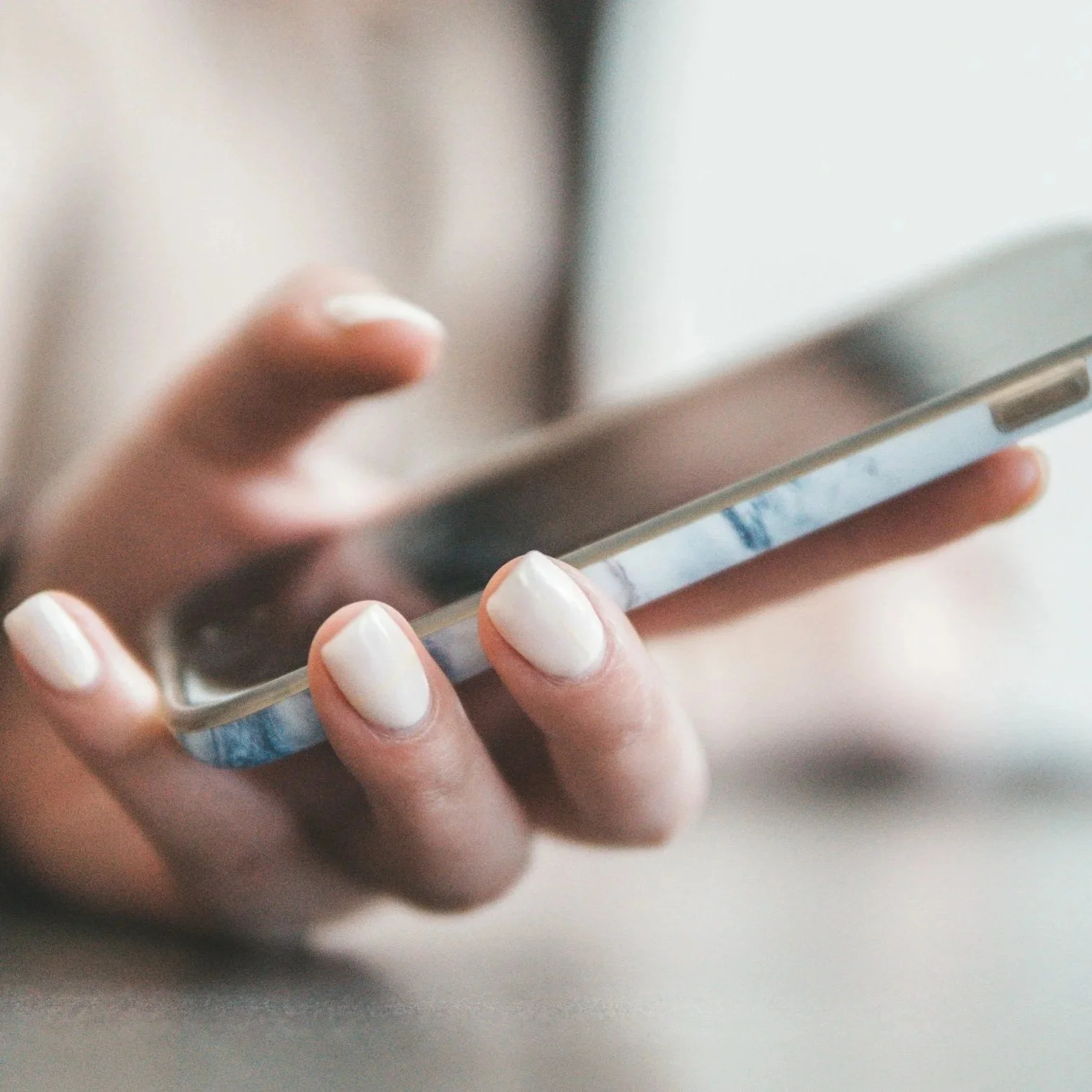 Close-up of a person holding a smartphone, focusing on their fingers and the device.