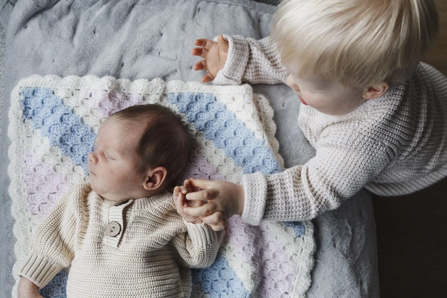 Newborn baby and his older brother holding hands