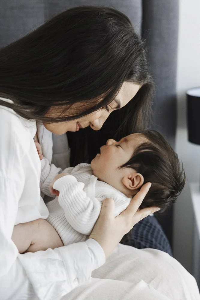 A woman holding a young child close, forehead against forehead in an intimate, tender moment.