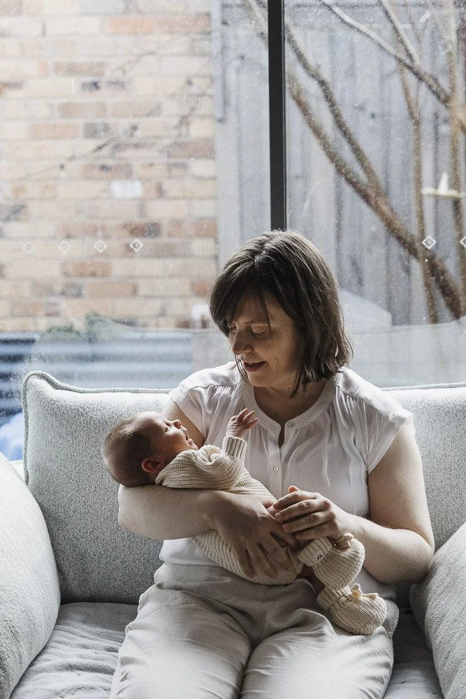 Mother and newborn son comfortable on the couch in front of the window