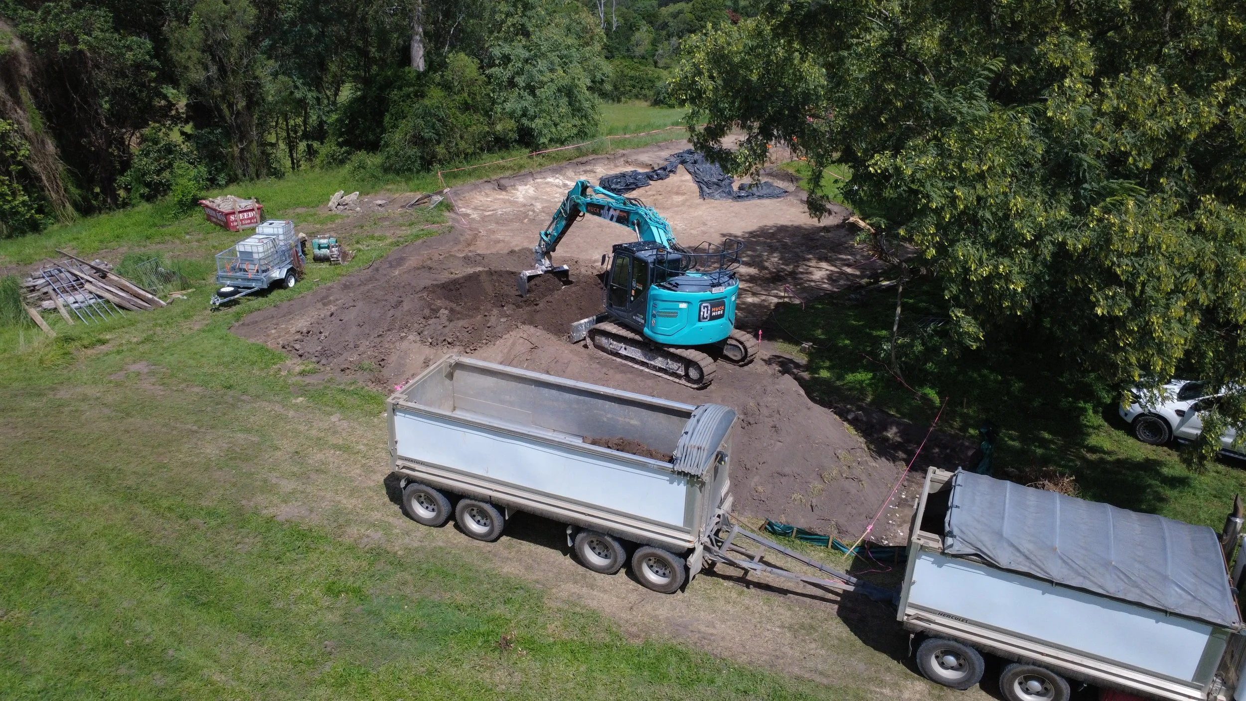 A large excavator loading soils into a truck waiting to head to a landfill on a construction site that requires dust, noise and vibration monitoring