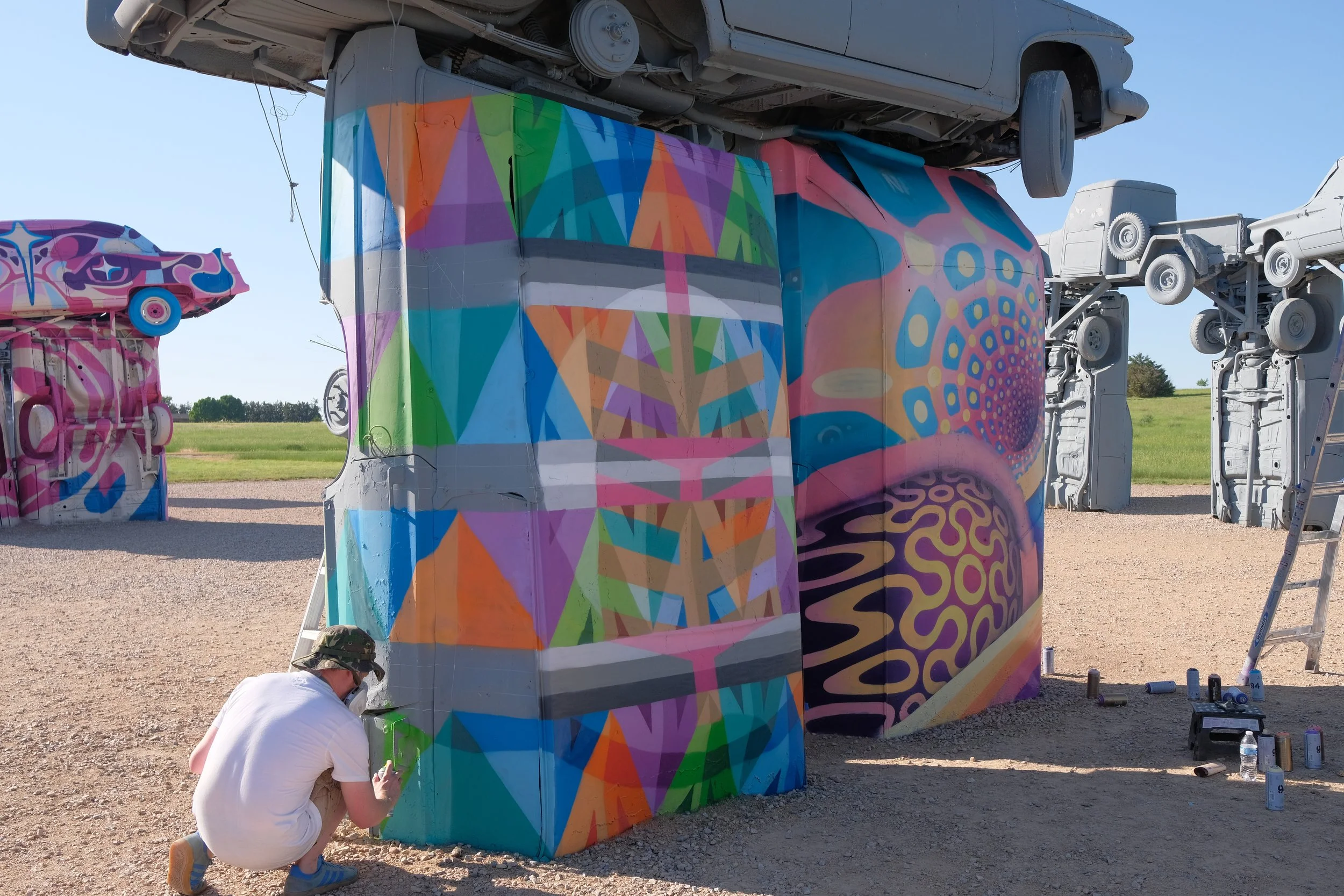 Paul Monsters working on one of the first carhenge murals in June of 2025, street art