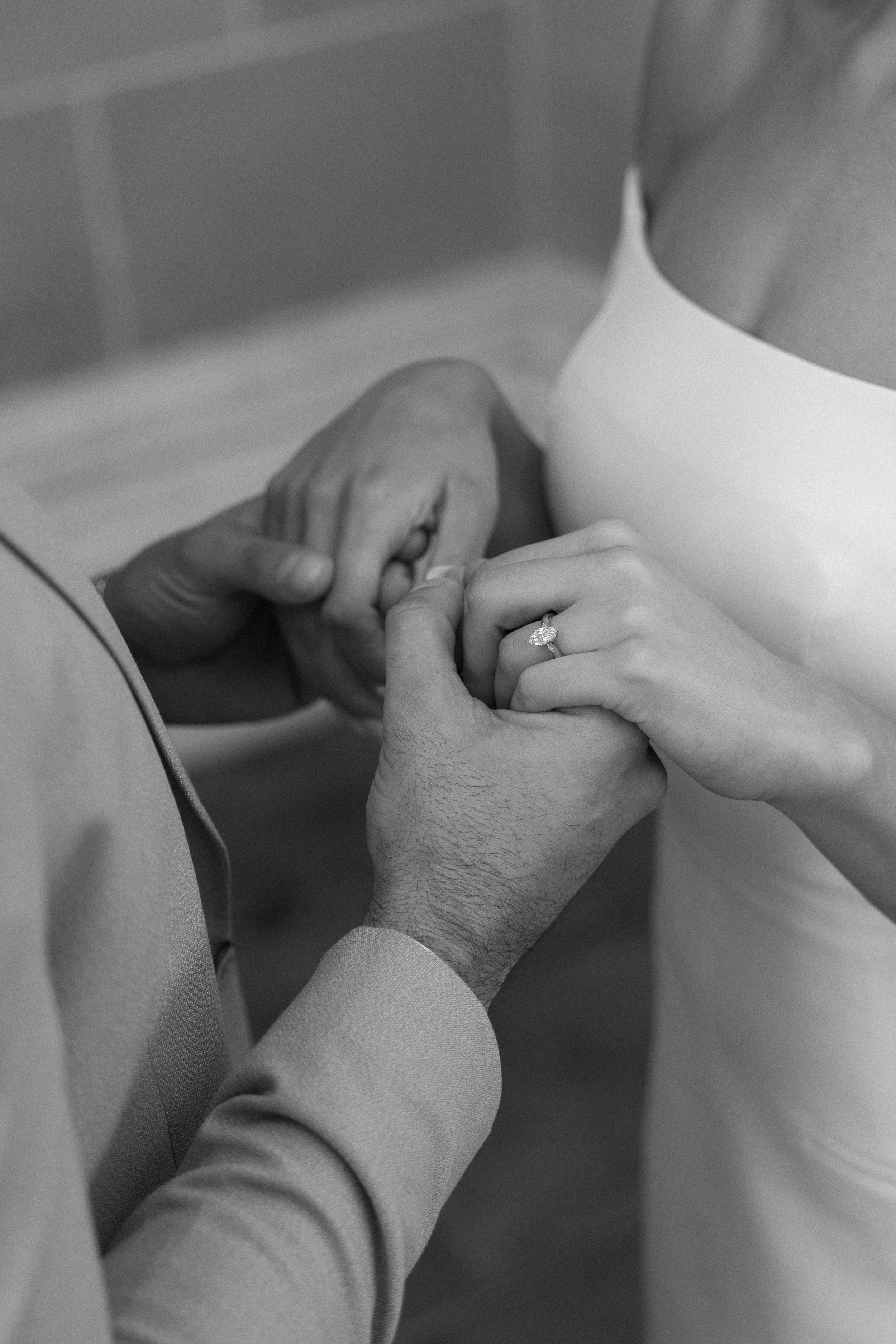 A couple holding hands during their wedding ceremony, with the focus on the woman's engagement ring.