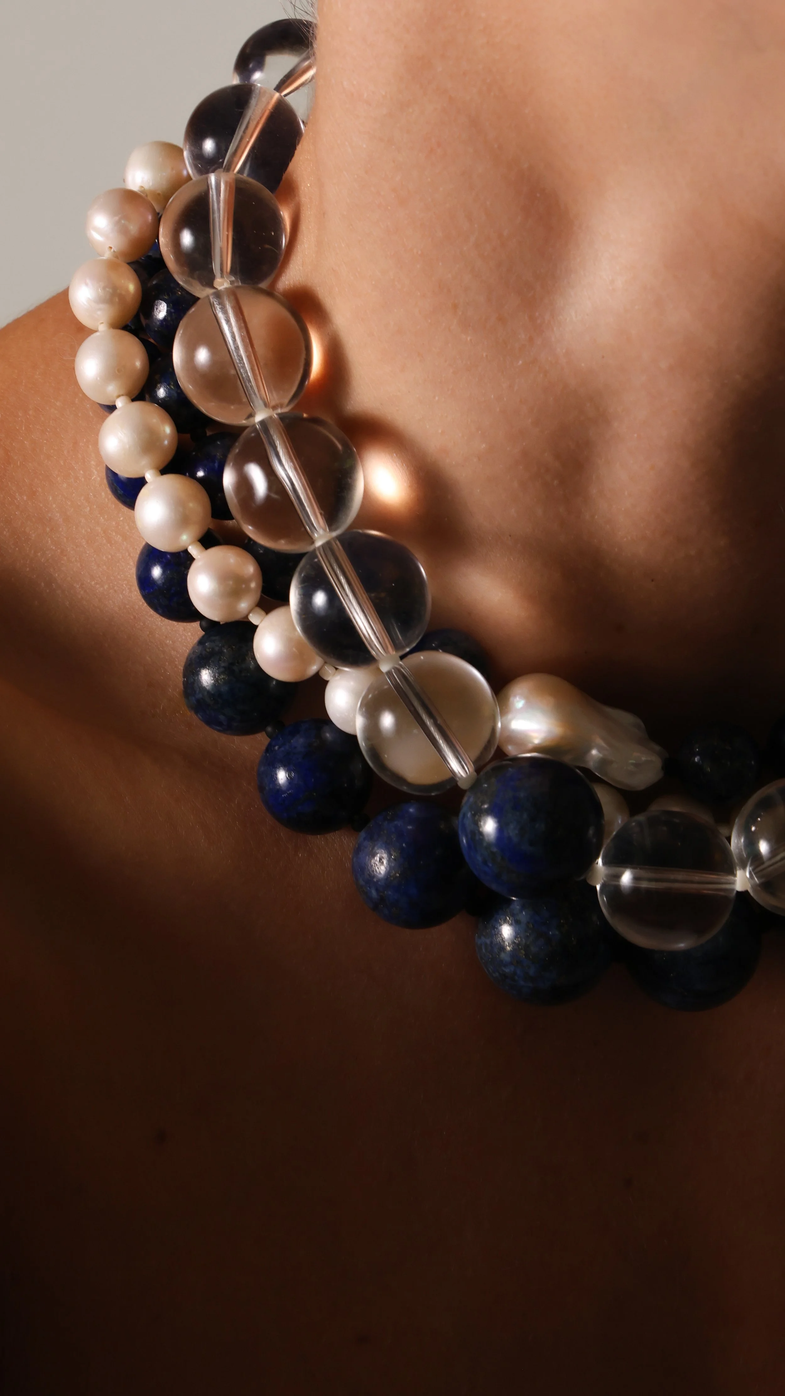 MODEL WEARING 3 NECKLACES MADE OF GLASS, PEARLS AND LAPIS LAZULI