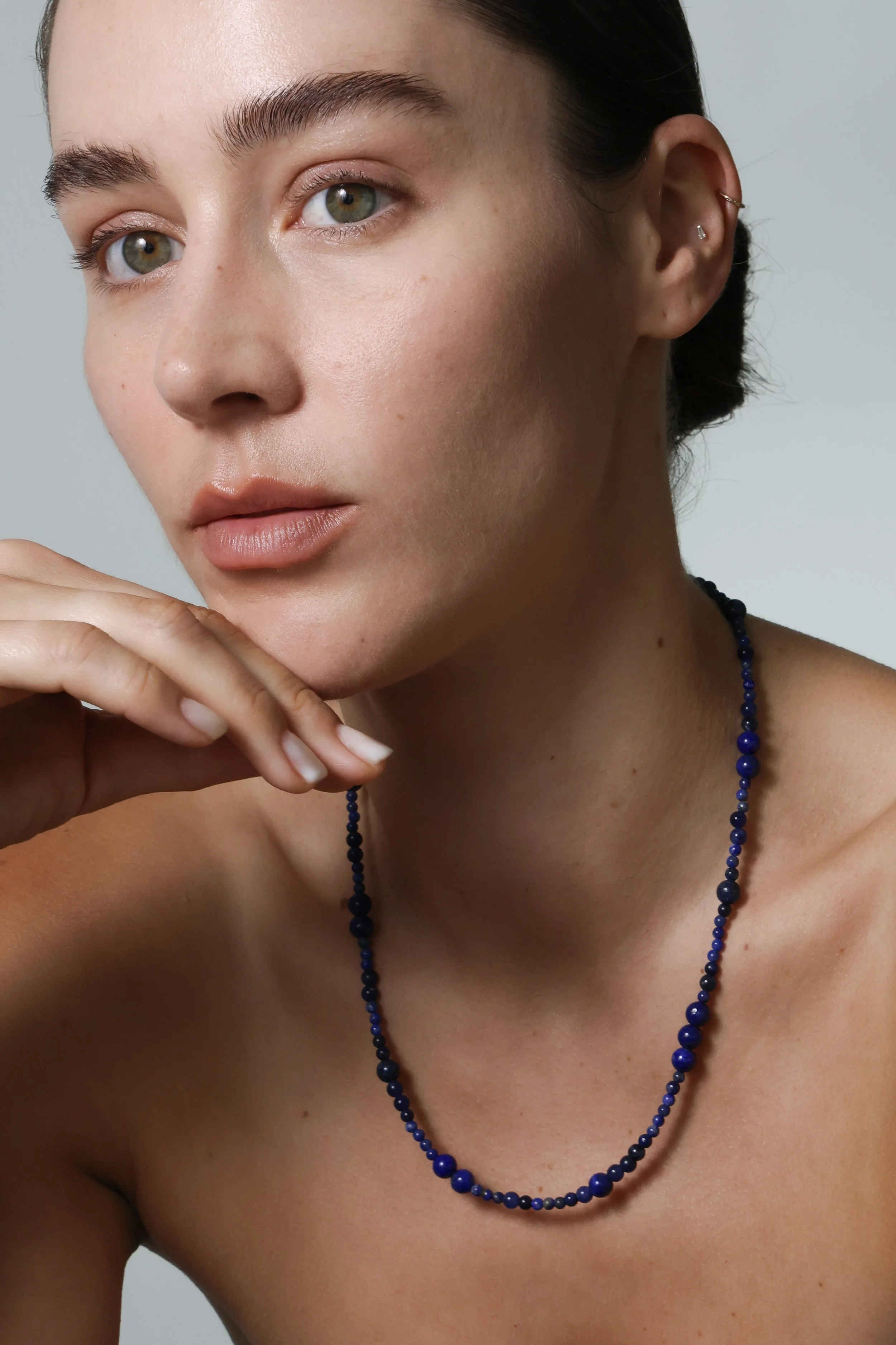 Model wearing a lapis lazuli necklace of different sized beads.