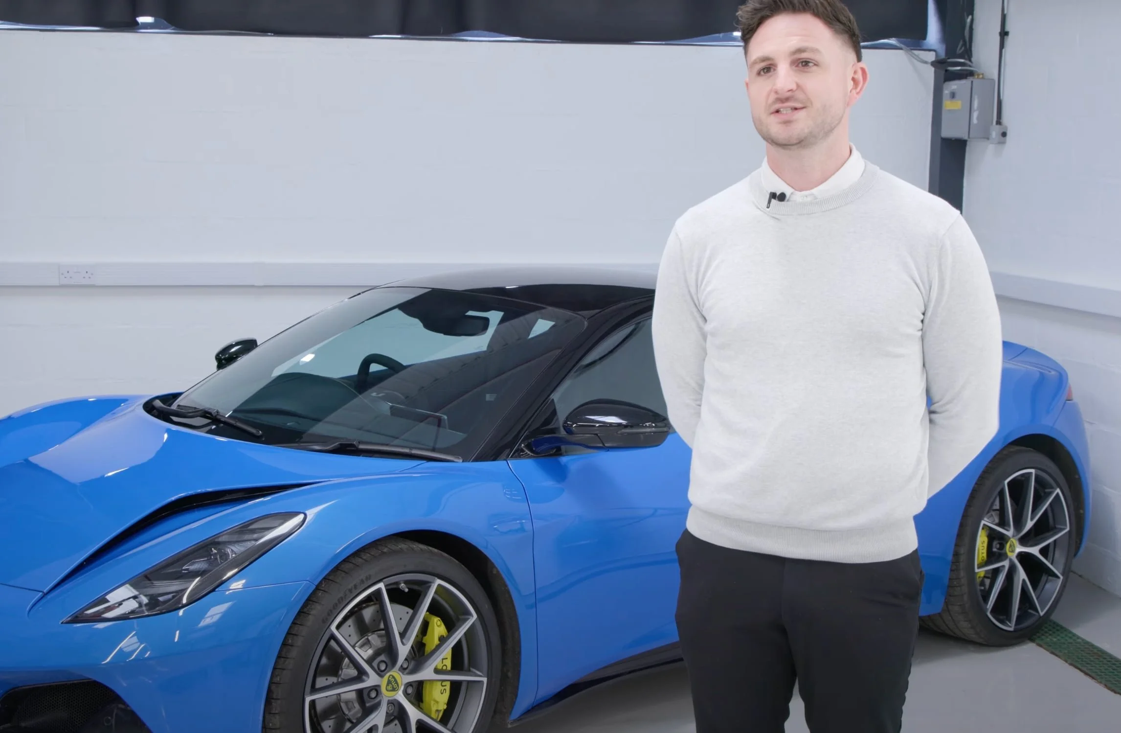 An engineering professional standing in front of a blue Lotus car in Lotus' training centre in Norwich