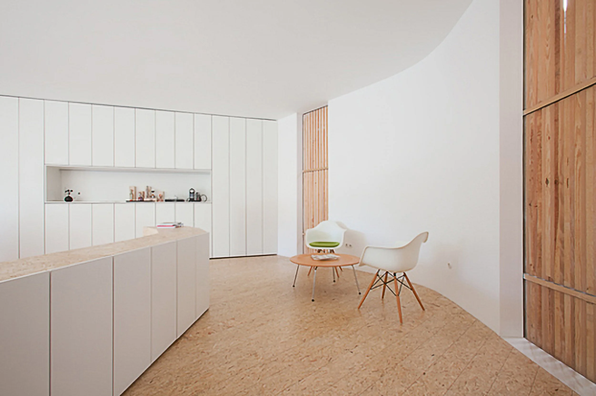 ADDESIGN ® Minimalist modern interior with white cabinetry, two white chairs, a small round wooden table, and wooden wall paneling.