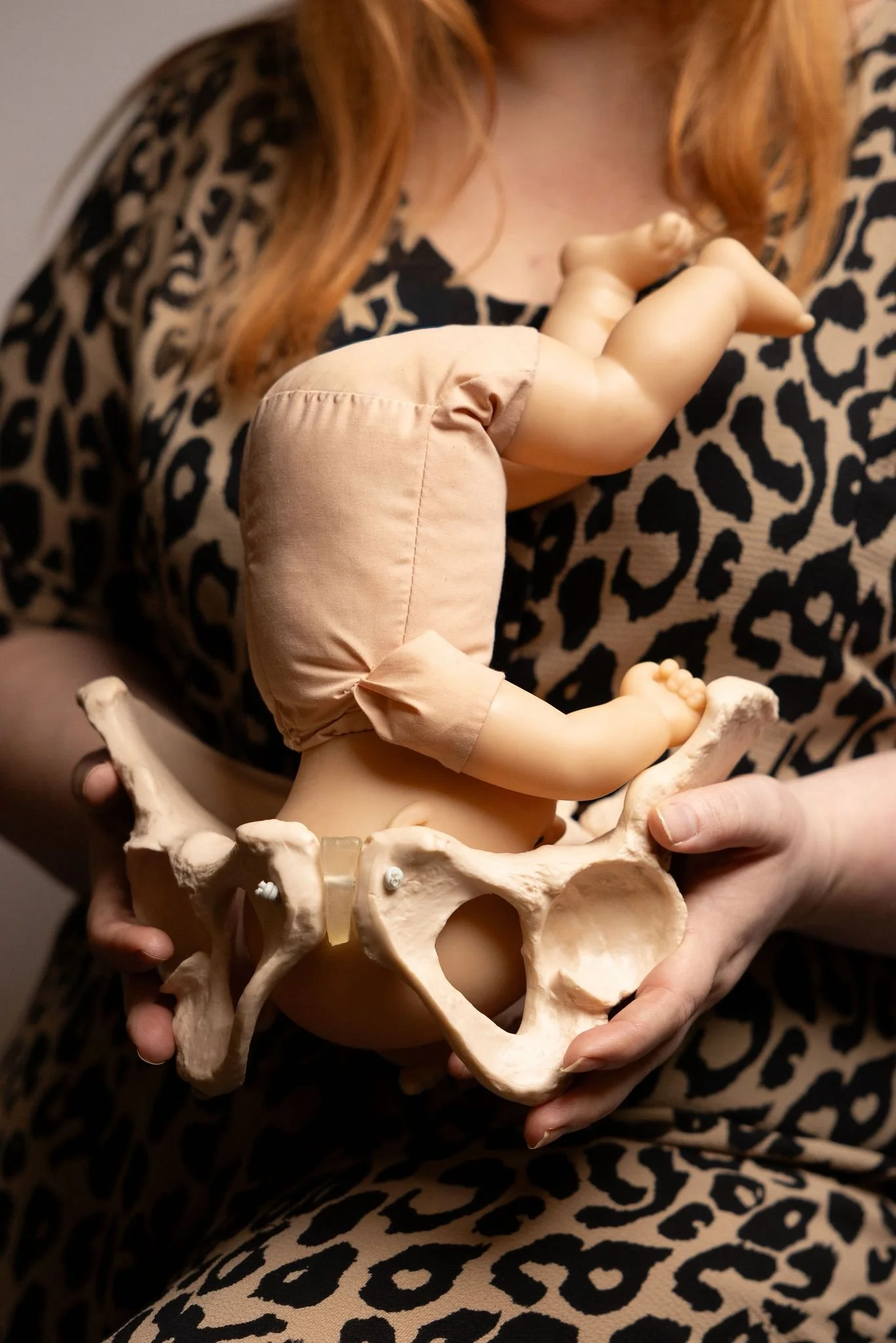 Midwife Natalie demonstrates in utero baby positioning using a doll and pelvis model in Warrington antenatal classes