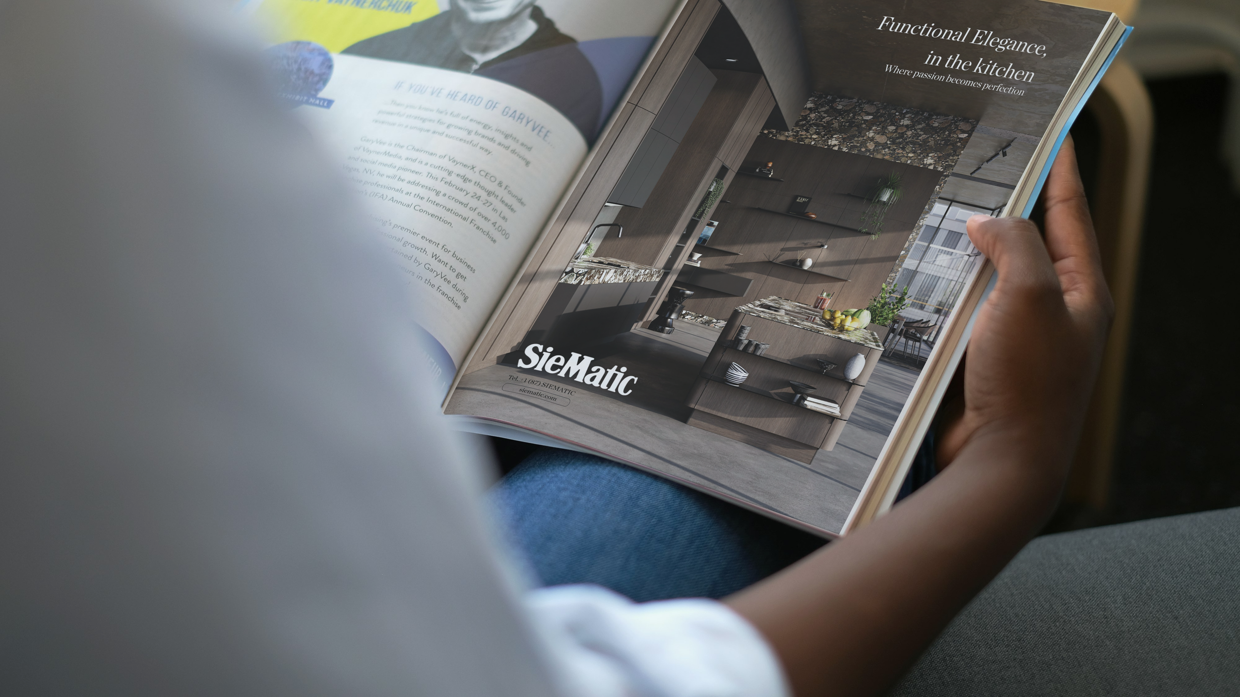Person holding an open magazine with an interior design advertisement featuring a modern kitchen with wooden cabinets, a marble island, and shelves, titled 'Functional Elegance, in the kitchen' with the Siematic logo at the bottom.