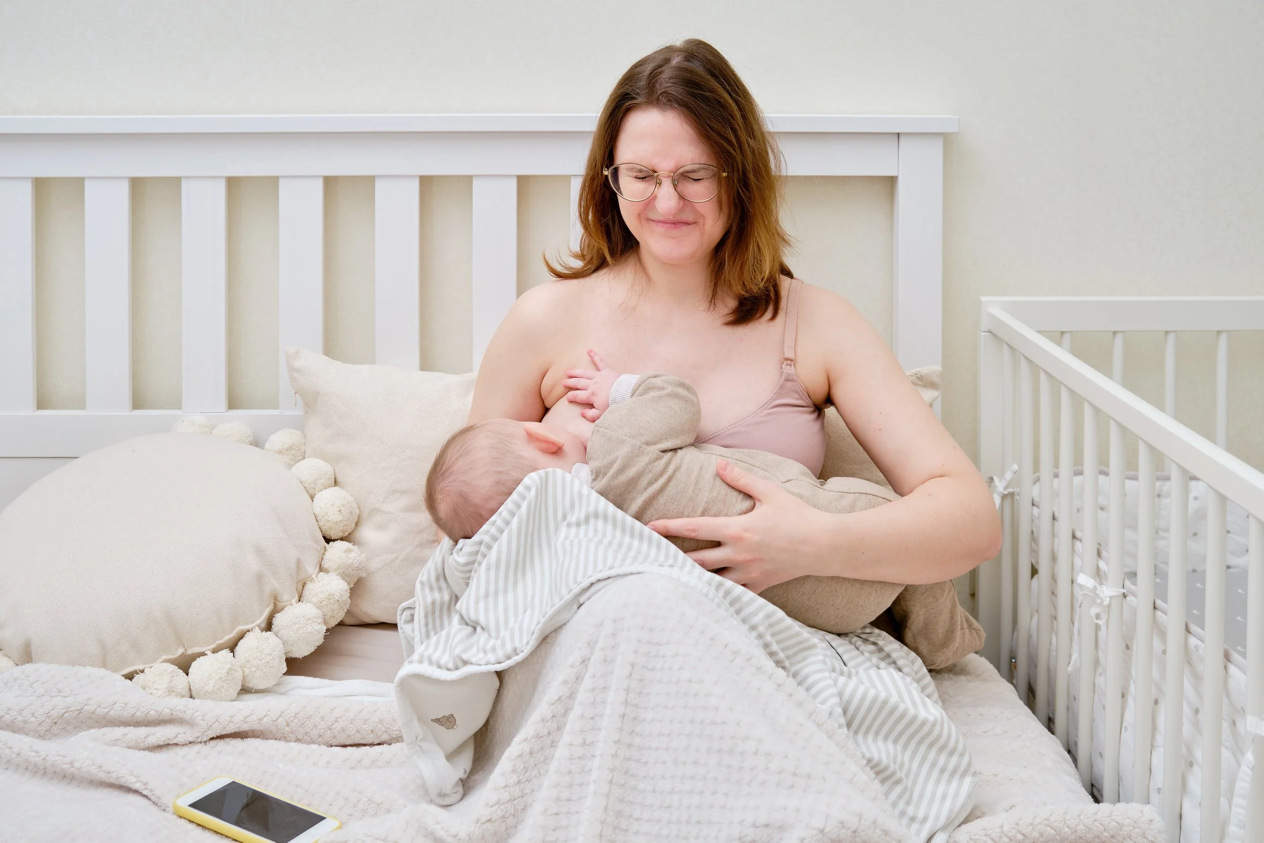 A mother experiencing pain with breastfeeding and getting help from a lactation consultant