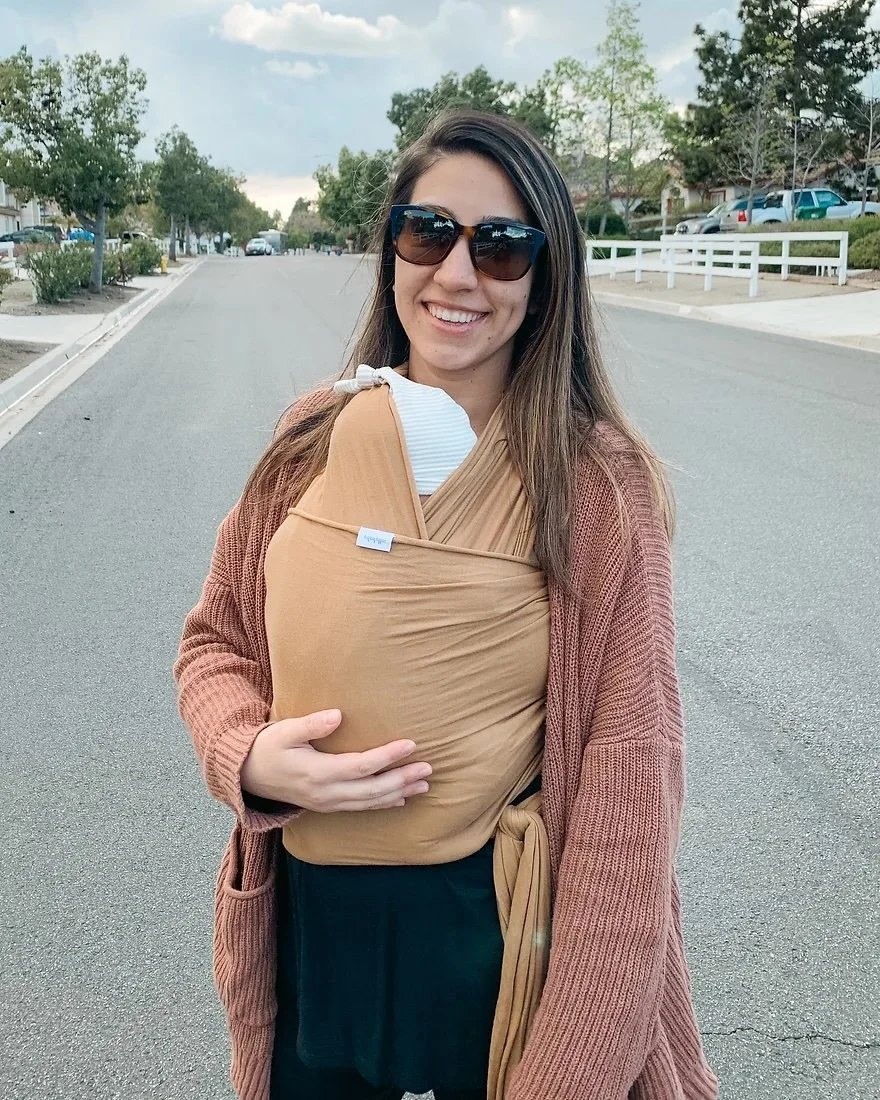 Jen Mendoza holding her new baby on her chest in a wrap on a walk