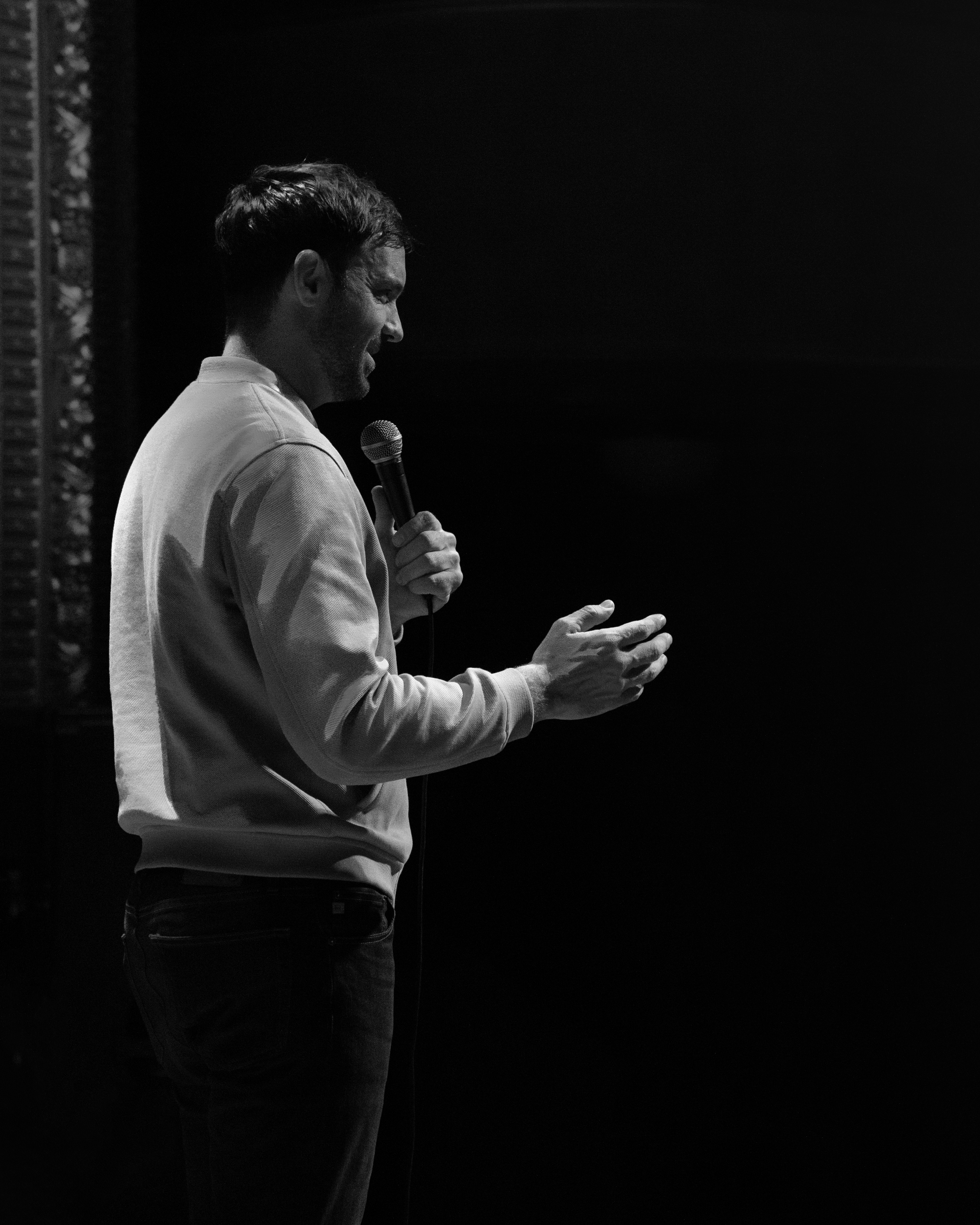 Black and white side shot of comedian Jeff Dye performing a live event during his tour, The Last Cowboy in L.A.
