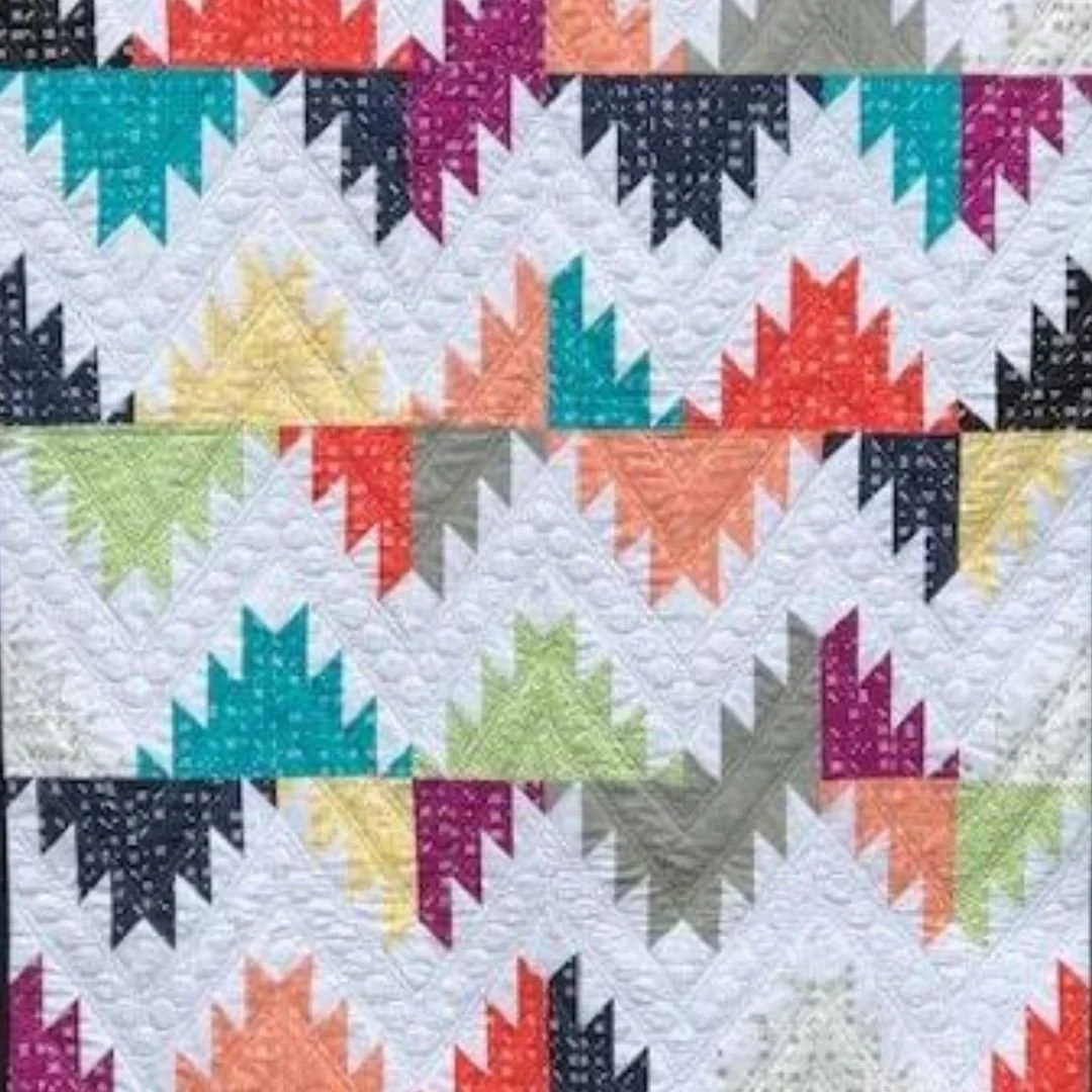 A colorful quilt with geometric star patterns created with various bright and pastel fabrics.