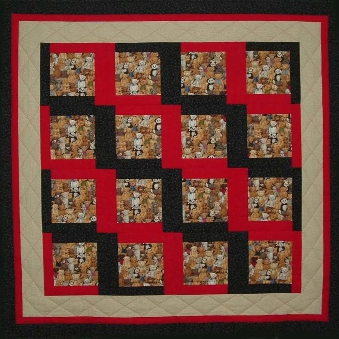 A quilt with a block pattern featuring teddy bears, pandas, and other animals, bordered by red, black, and beige strips.