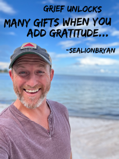 A smiling man with a beard and gray hair wearing a cap and purple shirt standing on a beach with the ocean and blue sky in the background. The overlay text reads: 'Grief unlocks many gifts when you add gratitude... -SealionBryan'.