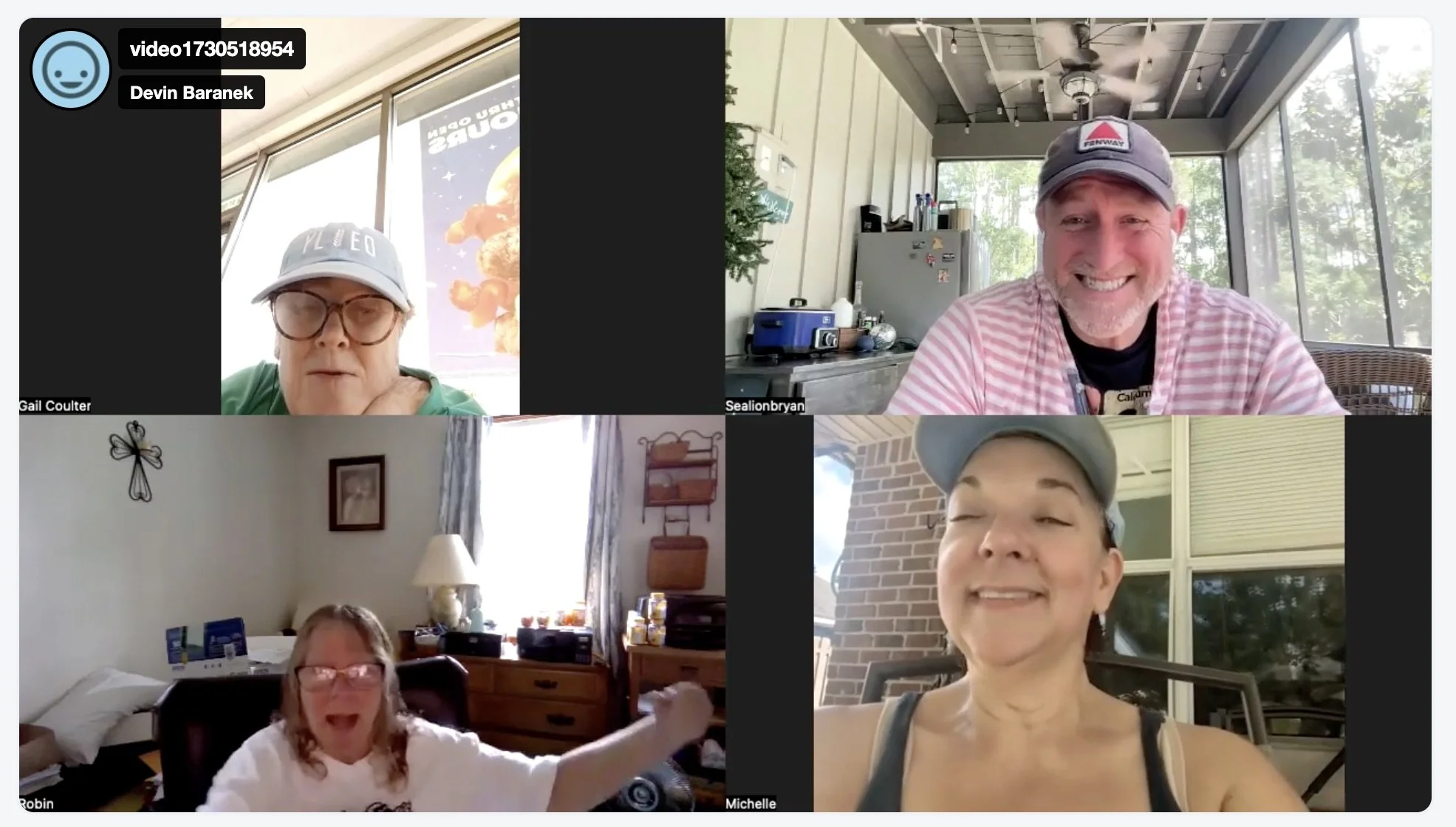 Screenshot of a virtual video call with four people, each in their own home. The top left person is a woman wearing glasses and a baseball cap, the top right is a man smiling wearing a cap, the bottom left is a woman in a white shirt with glasses, and the bottom right is a woman wearing a gray cap.