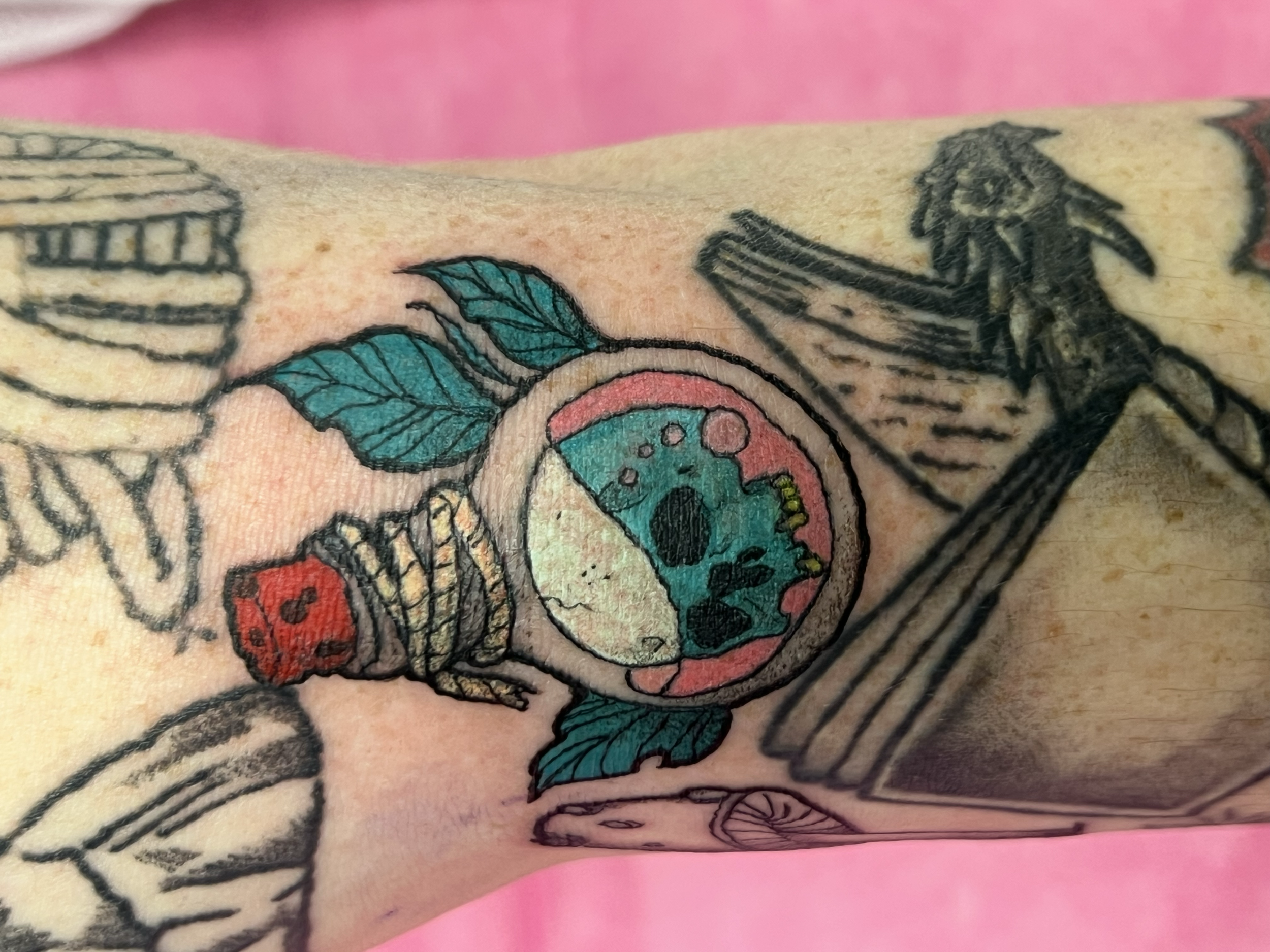 Close-up of a colorful tattoo featuring a skull, leaves, and blurred objects on skin.