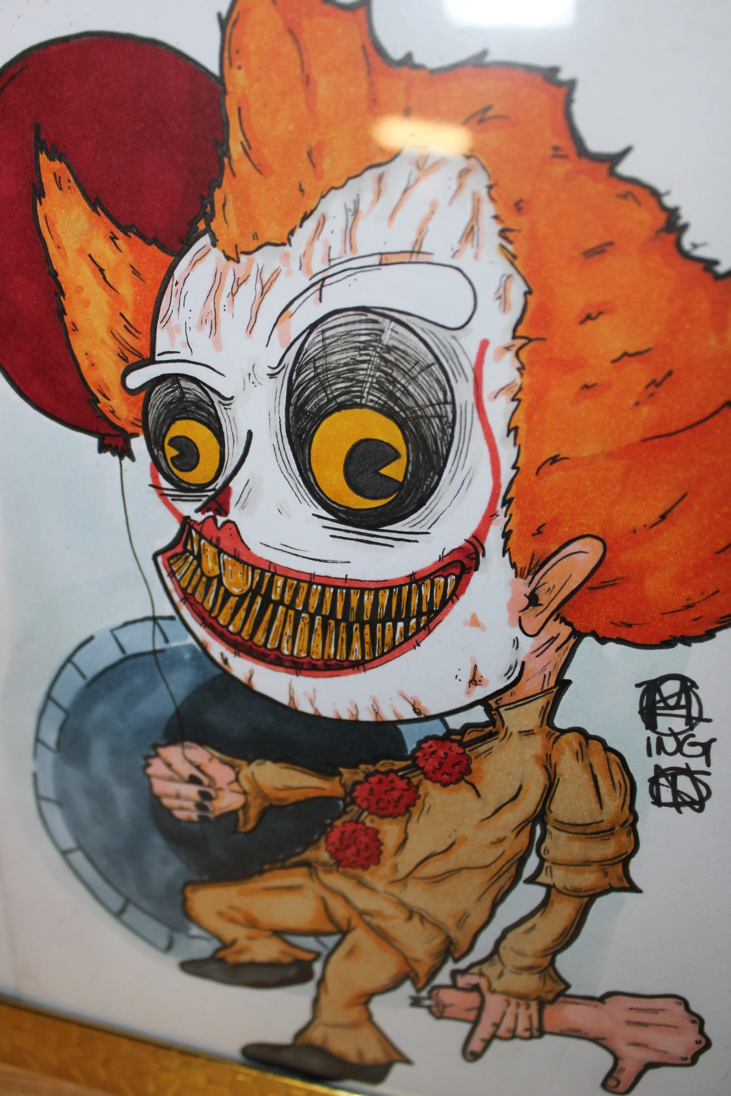 Colorful cartoon drawing of a clown with orange hair, big yellow eyes, a red nose, and a wide, yellow, jagged-tooth grin. The clown is wearing a yellow and brown striped clown outfit with red pom-poms and is holding a tray.