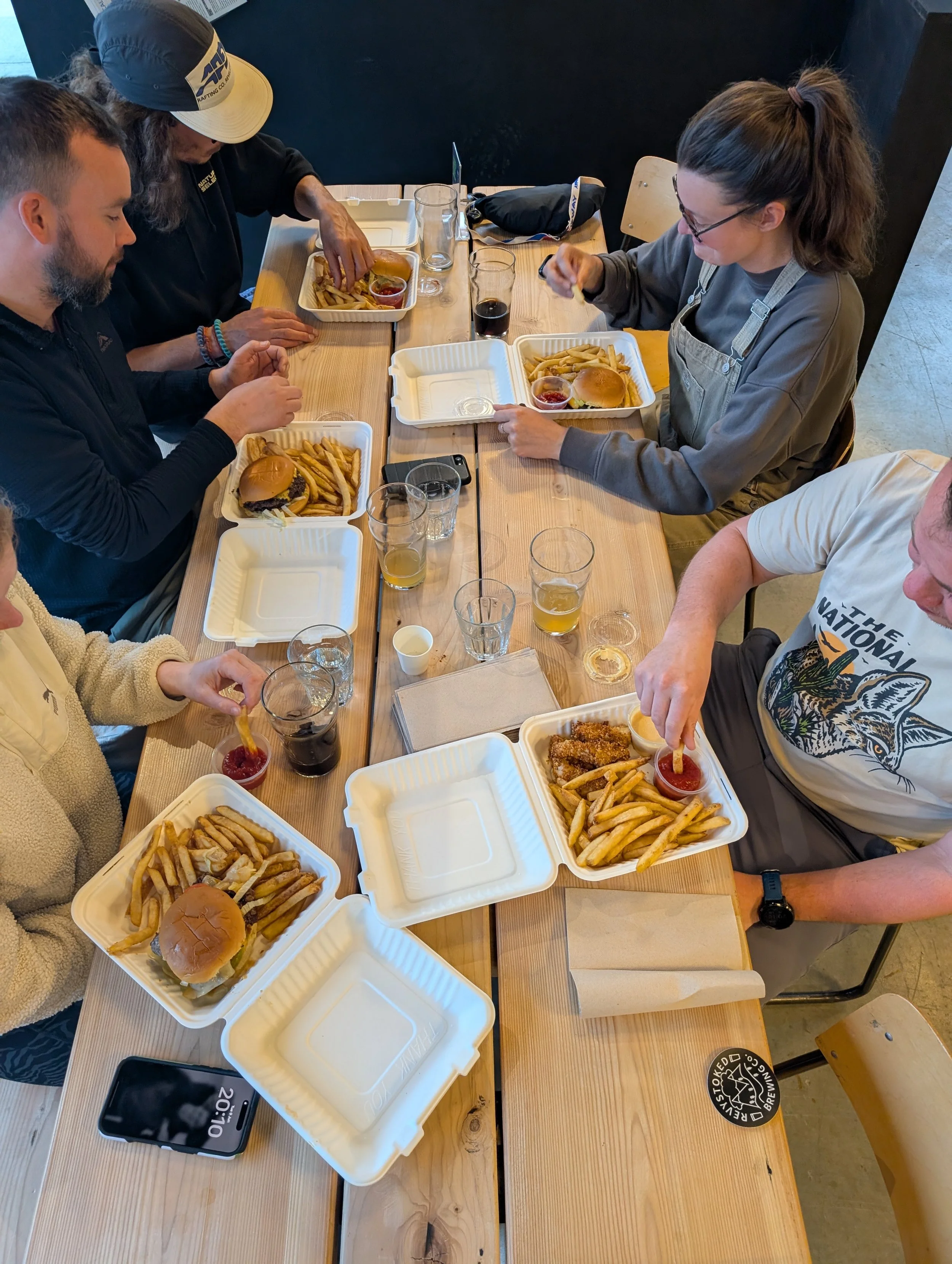 Top-down photo of people eating burgers and fries around a wooden table