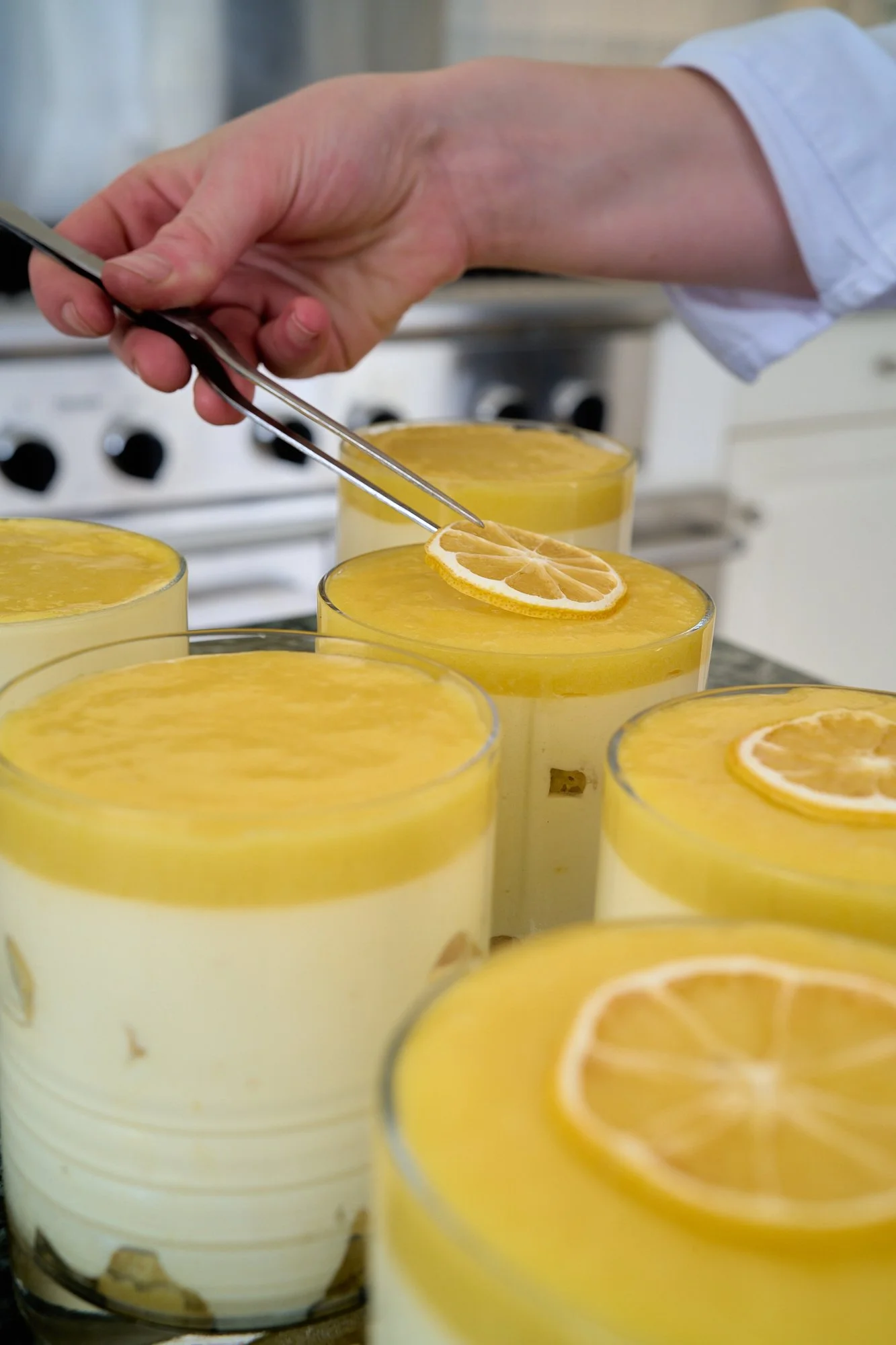 Glasses of lemon mousse topped with lemon slices on a kitchen counter.
