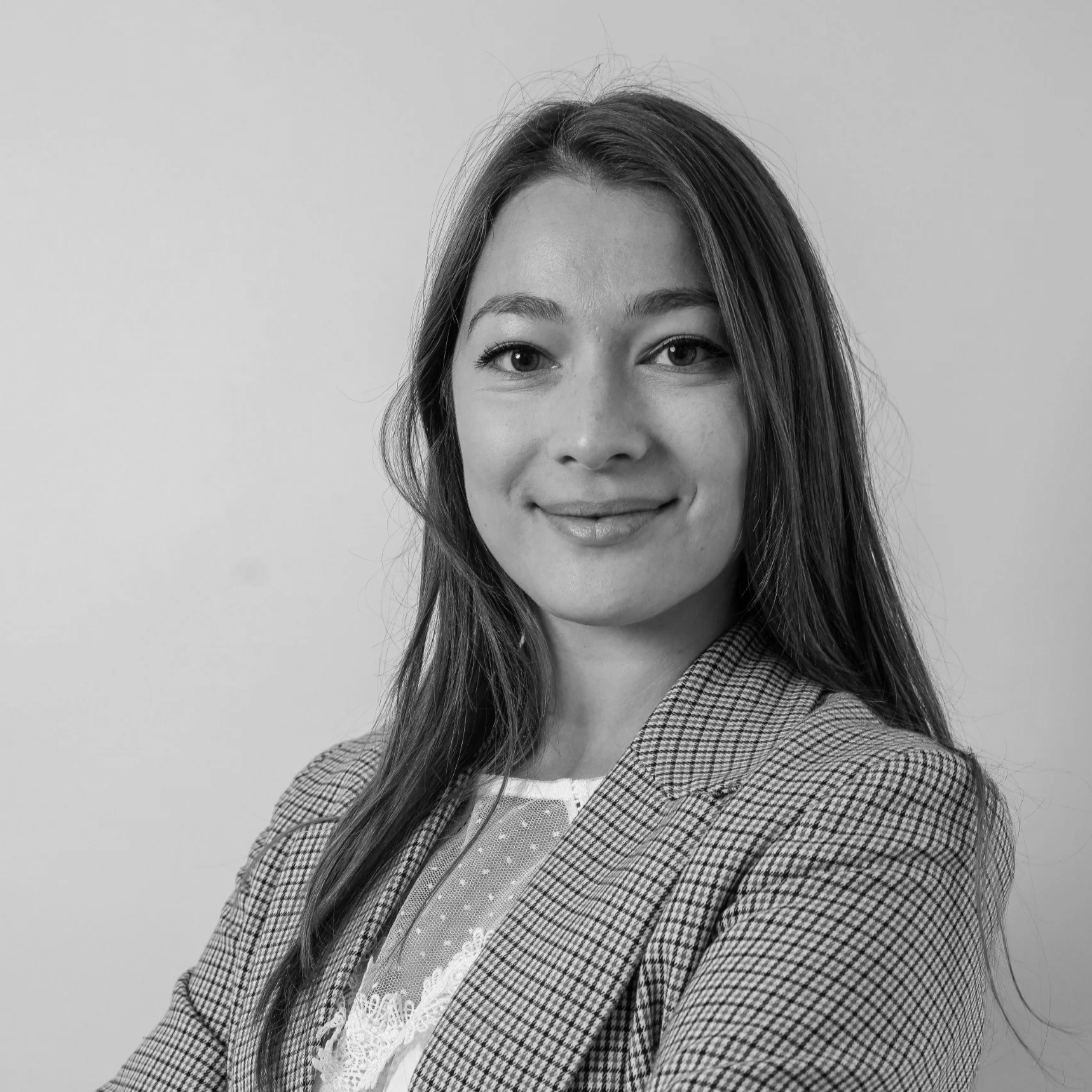 Portrait professionnel en noir et blanc de Klélia Delétang portant une veste à carreaux et une chemise à la dentelle.