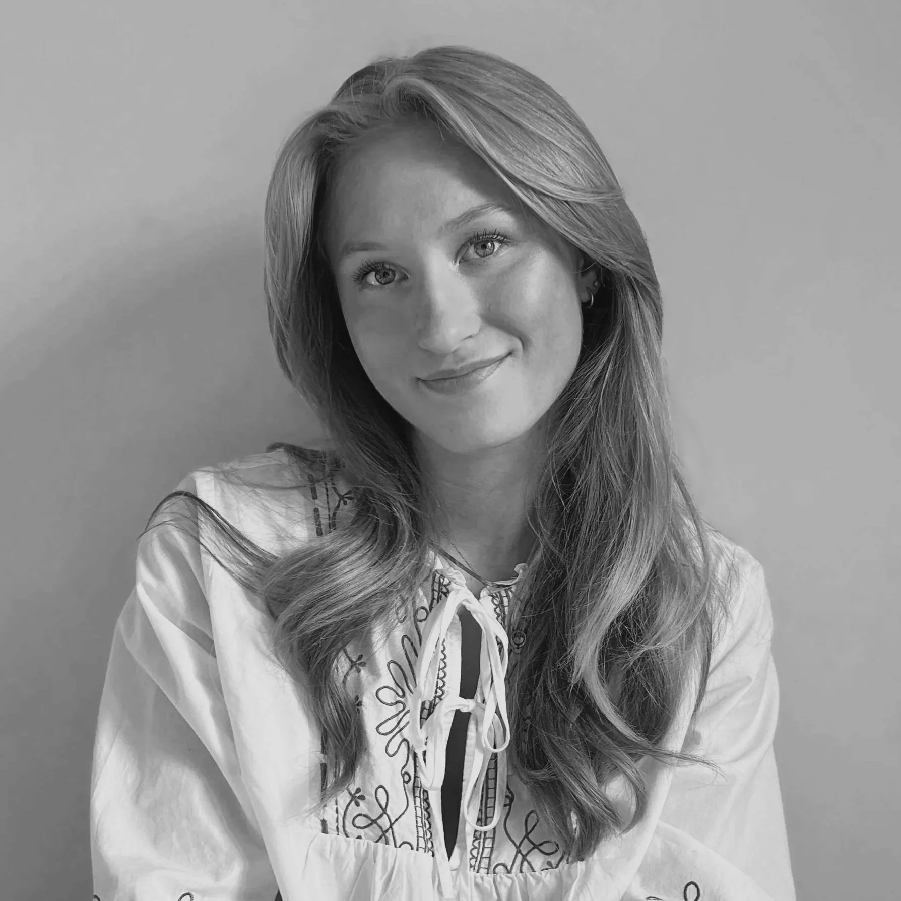 Portrait d'une femme avec des cheveux longs et bouclés, souriant, en noir et blanc.