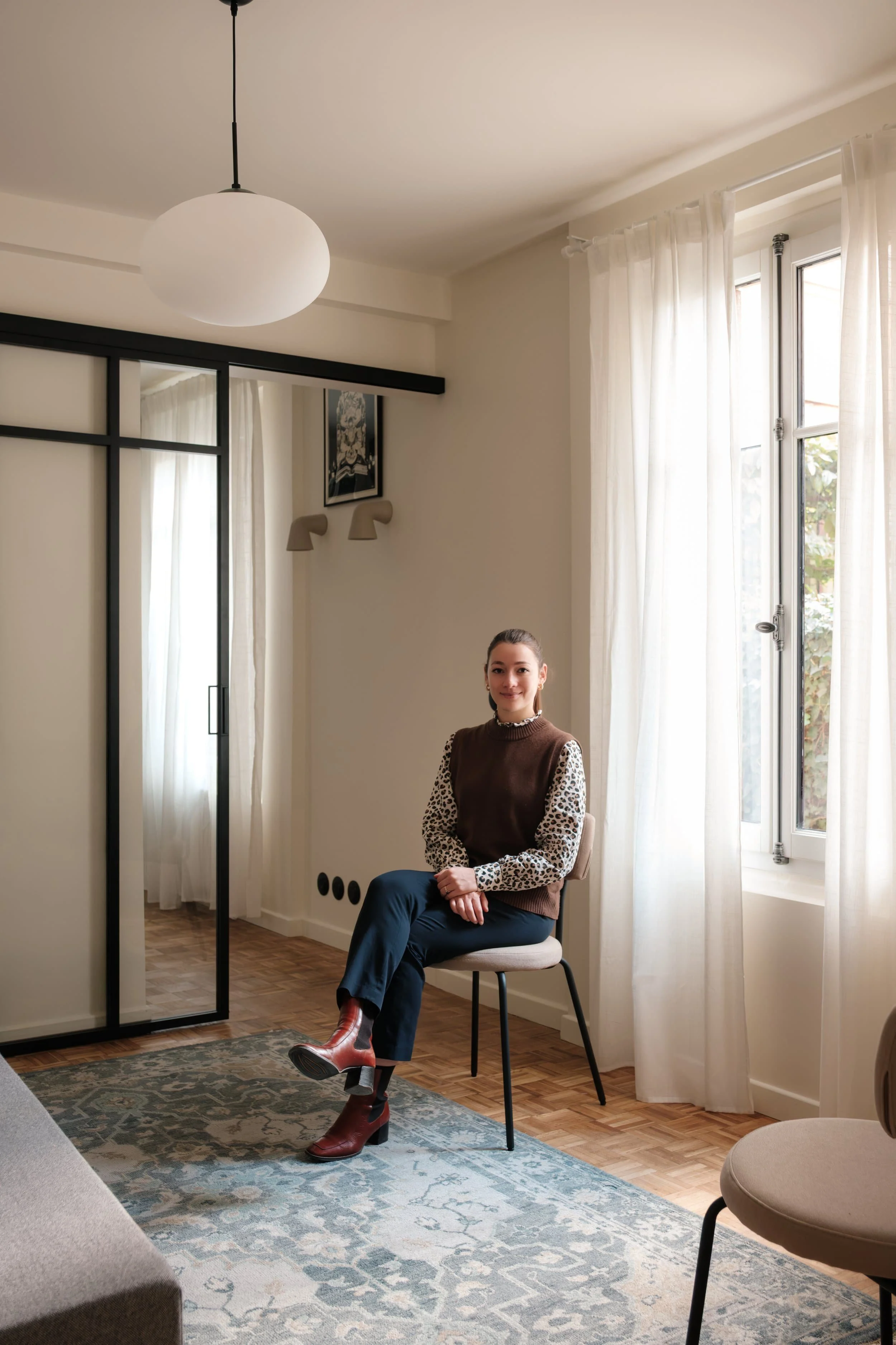 Klélia Delétang Architecte d'intérieur assise sur une chaise dans un intérieur rénové
